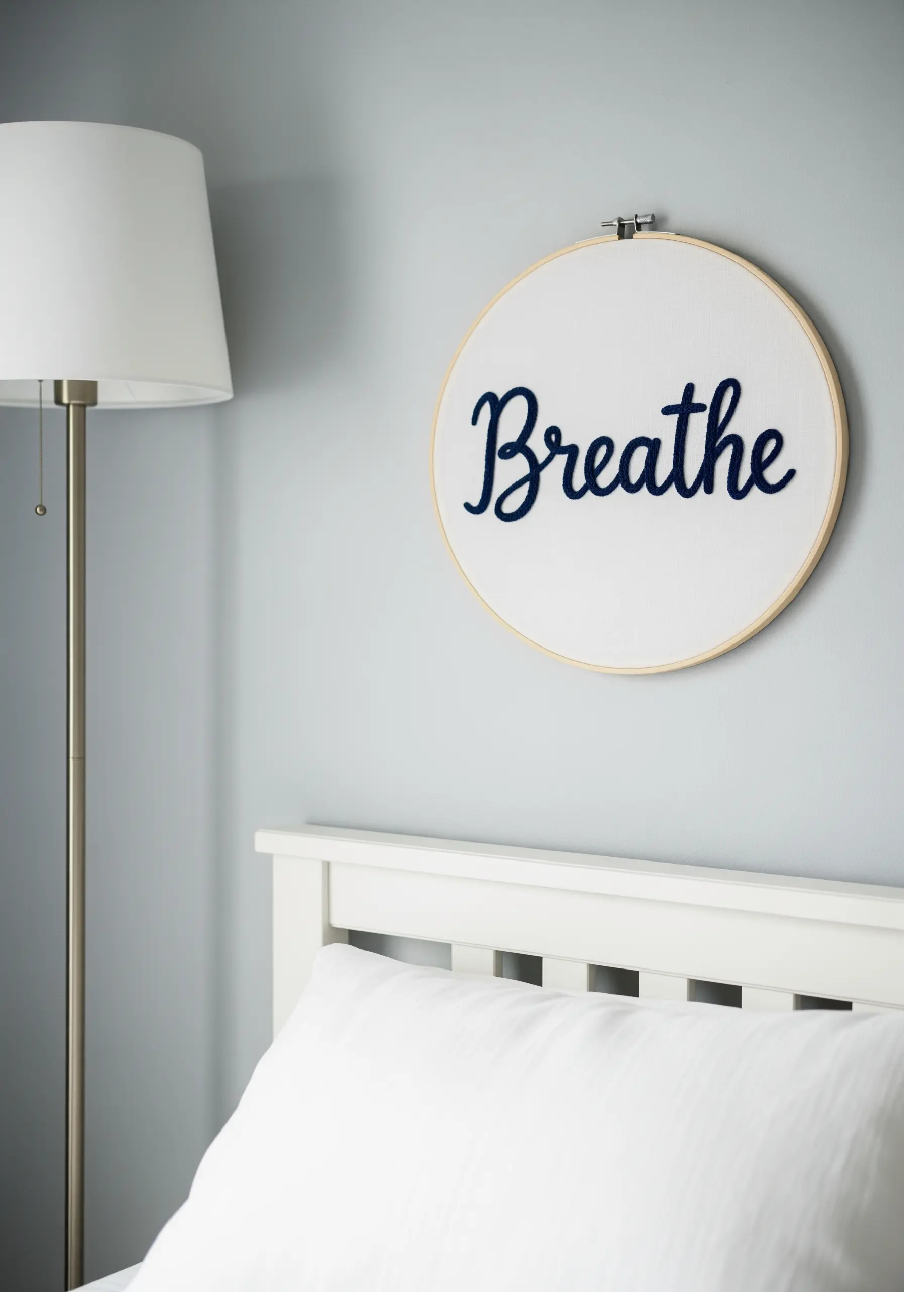 An embroidery hoop with the word 'Breathe' stitched in raised navy blue thread.