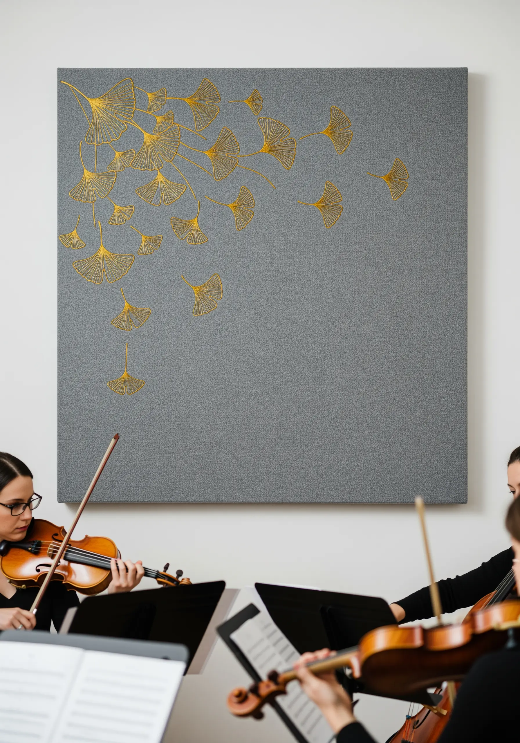 Golden ginkgo leaves embroidered with metallic thread, cascading down a grey canvas.
