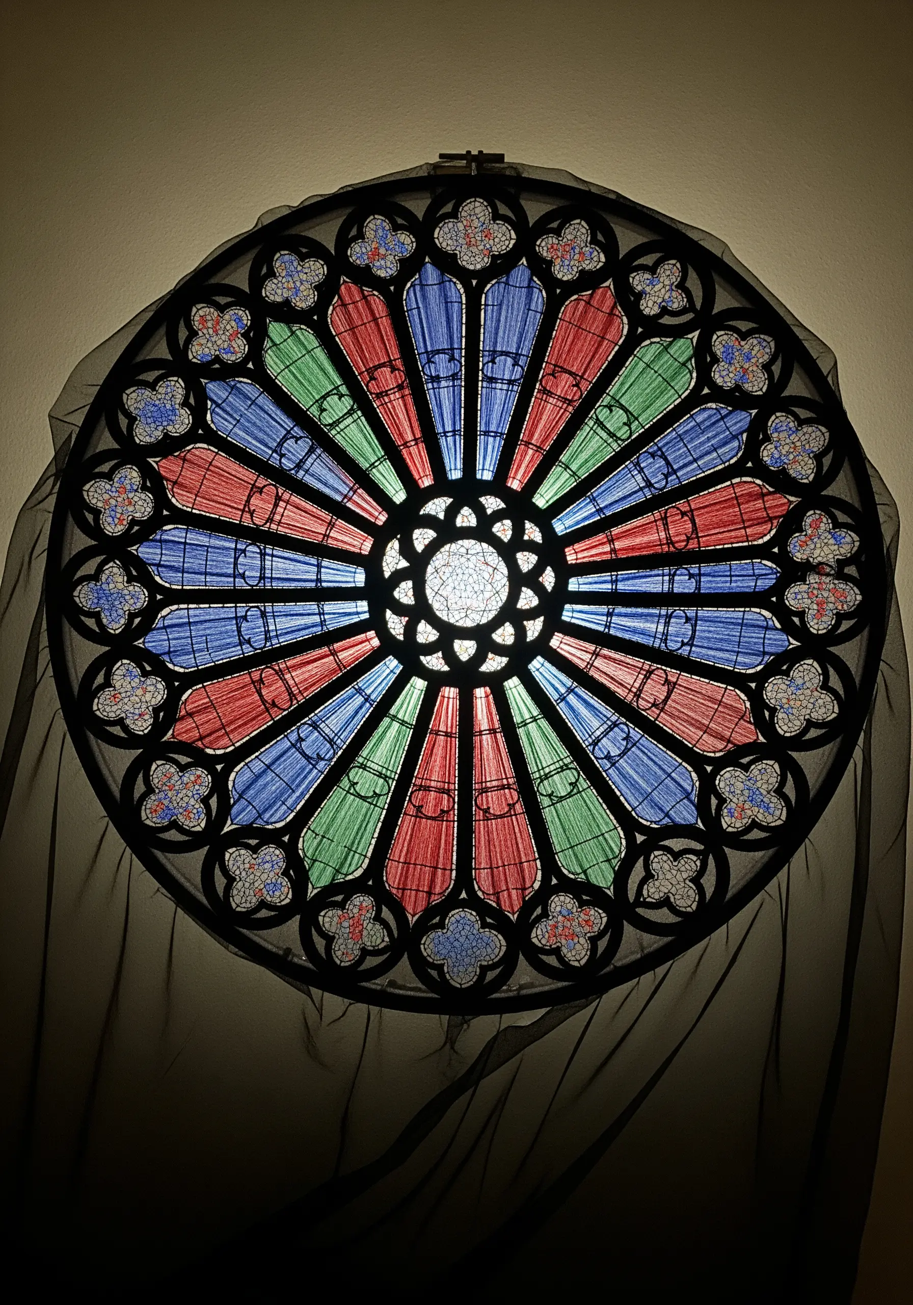 An embroidery hoop depicting a Gothic cathedral's rose window with black outlines.