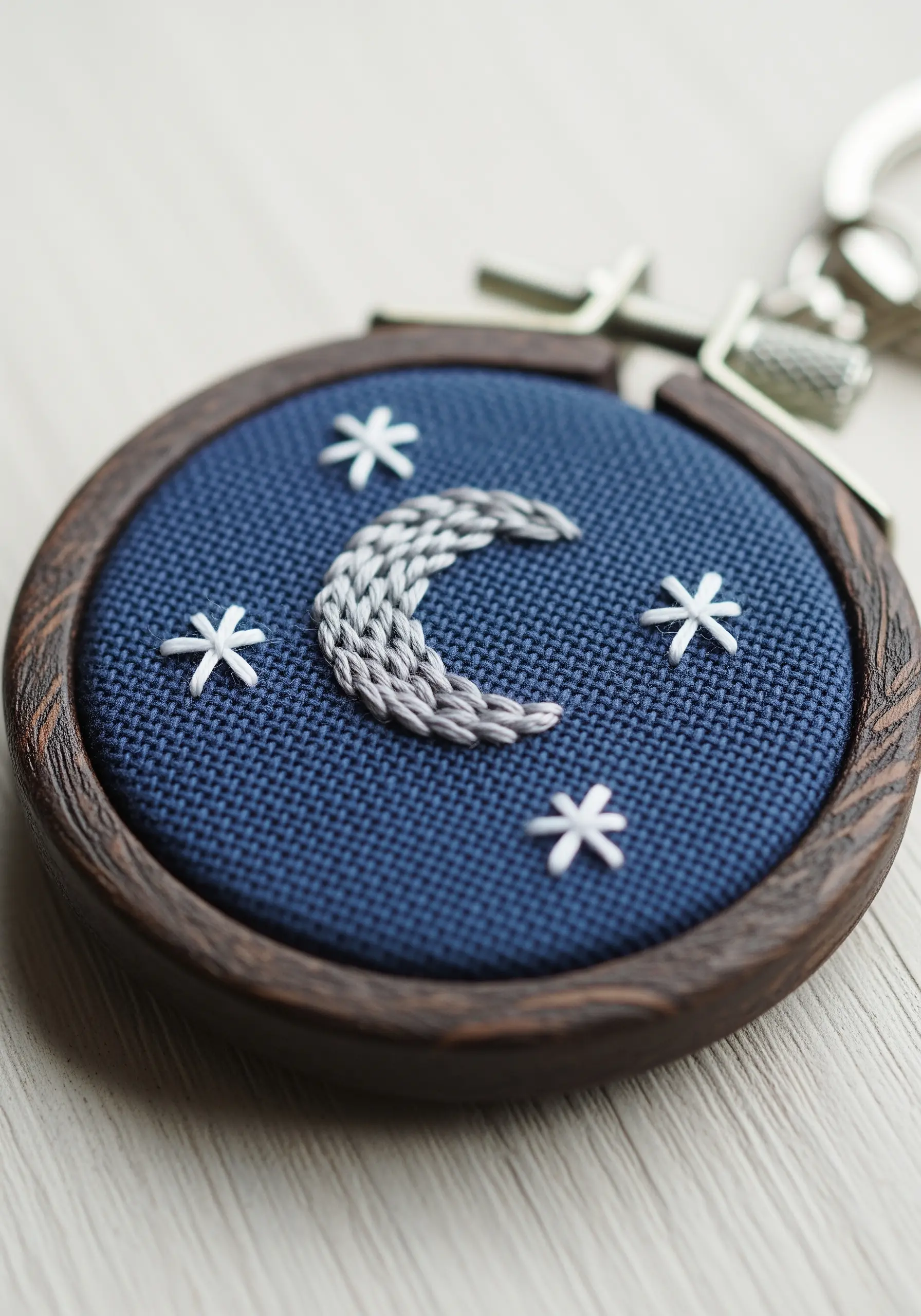 Chain-stitched crescent moon with a gray gradient on dark blue fabric