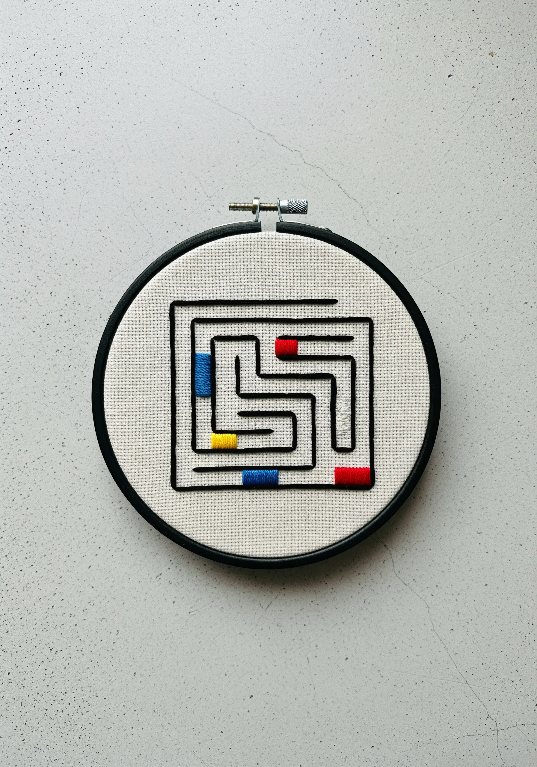 A clean, geometric maze embroidered with black whipped backstitch and color blocks.
