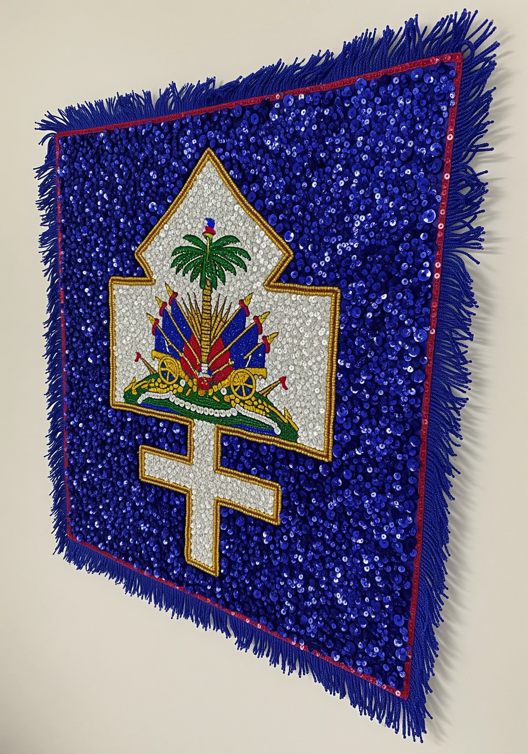 A Haitian Vodou flag heavily embellished with blue and white sequins and a central emblem.