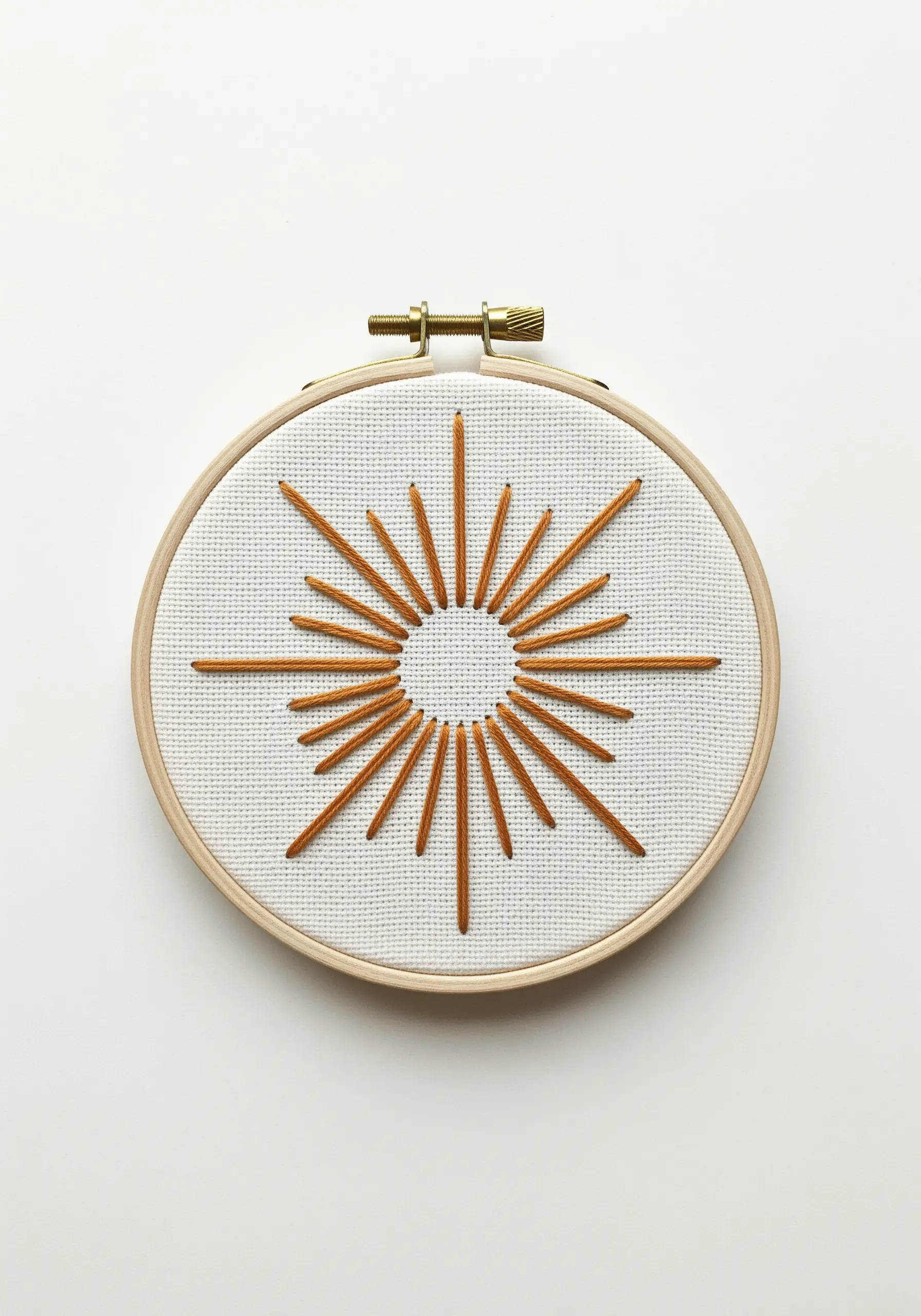 A minimalist sunburst motif with orange straight stitches on white Aida cloth.