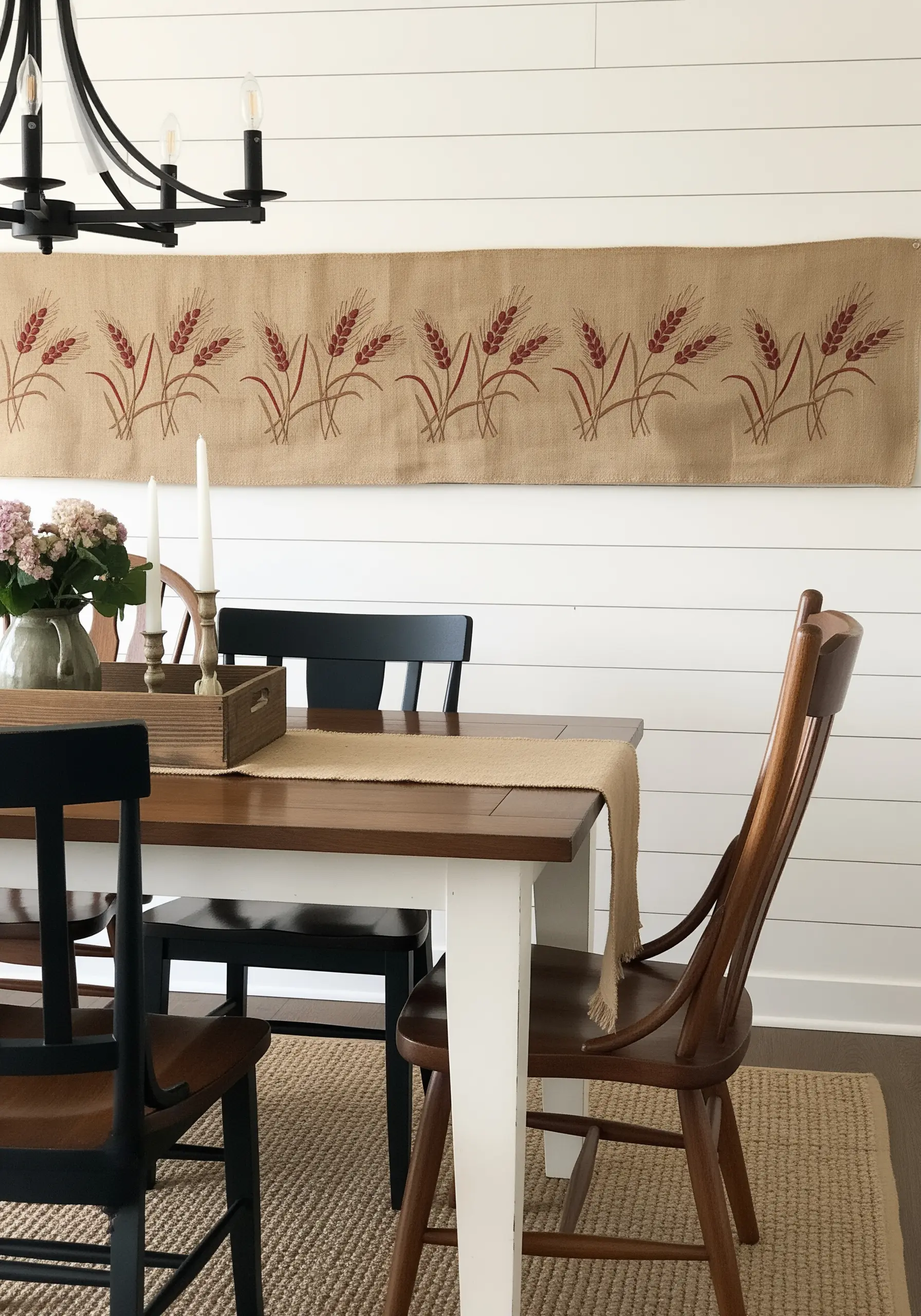 A long burlap table runner embroidered with repeating motifs of red wheat stalks.