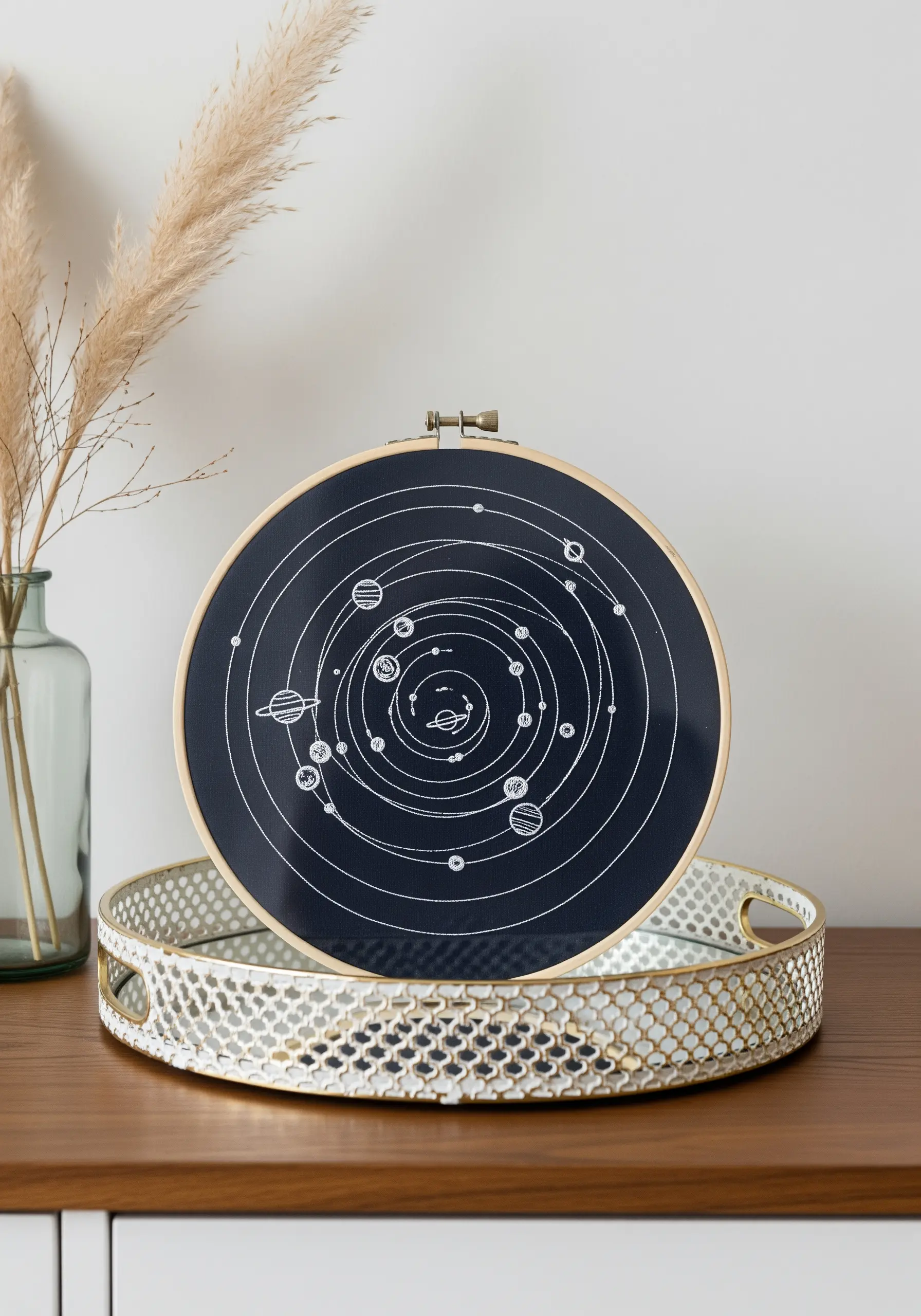 White thread embroidery of the solar system on a black fabric background in a hoop.