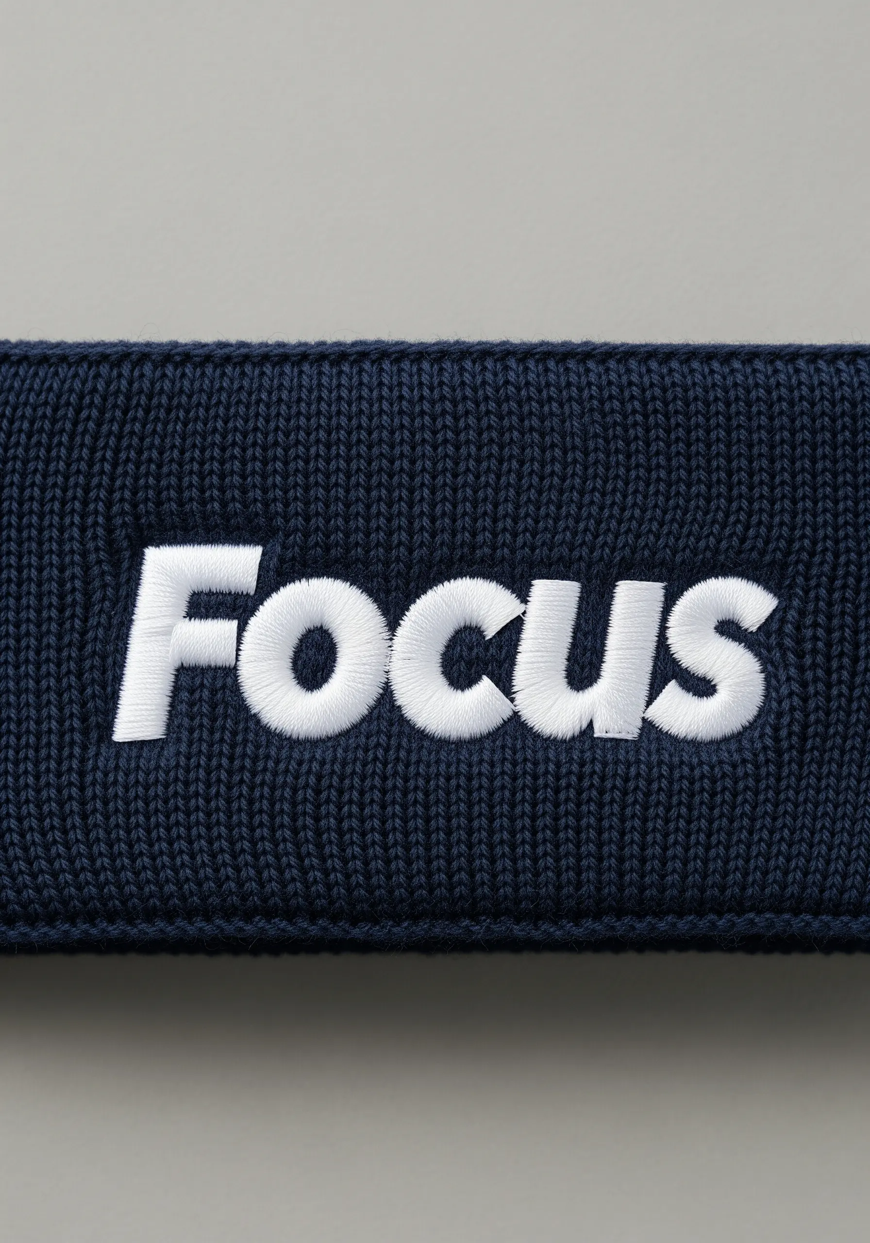 Bold white satin-stitched word “Focus” on a navy blue ribbed headband.