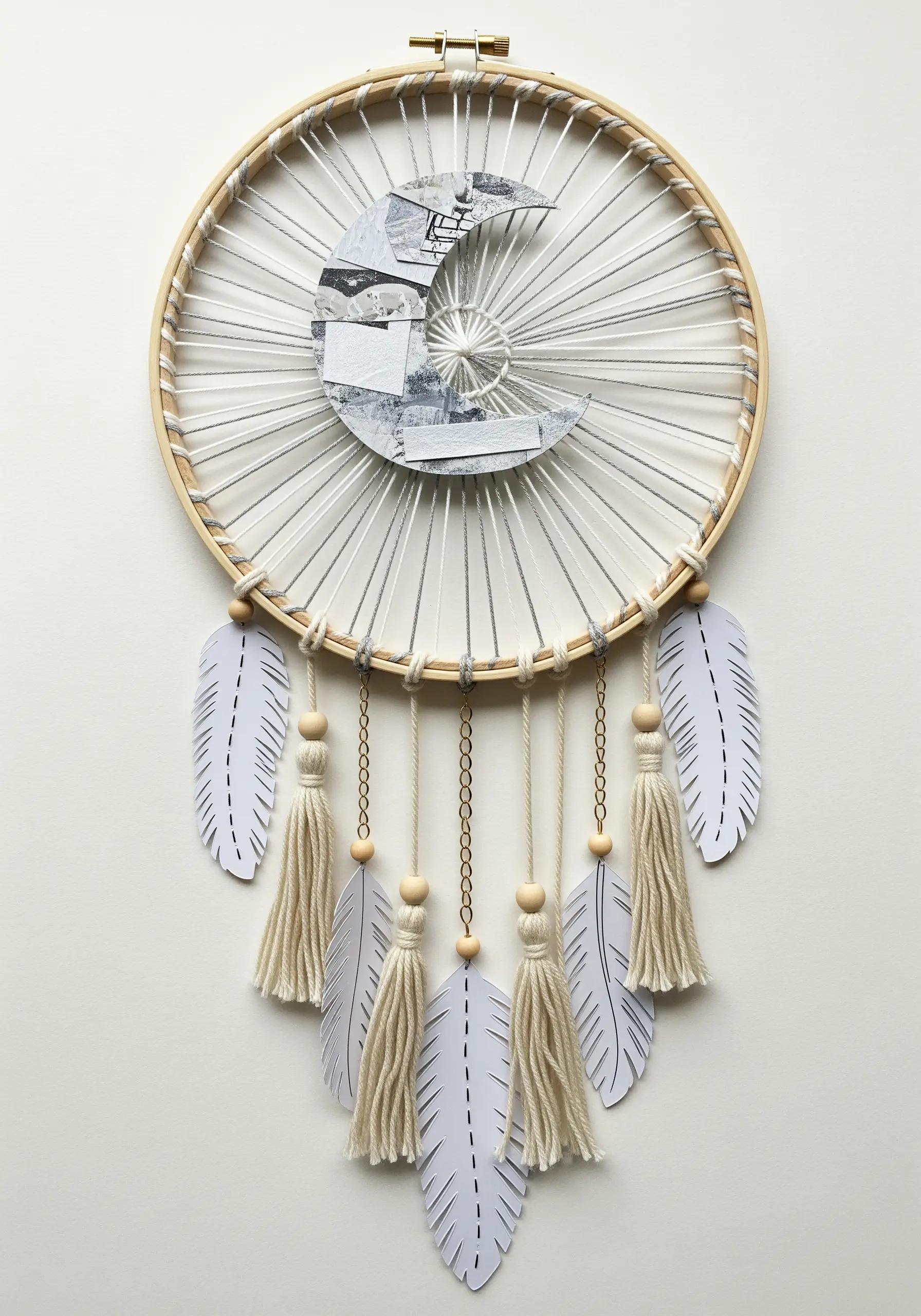 A dreamcatcher made in an embroidery hoop with a woven thread web and paper collage elements.