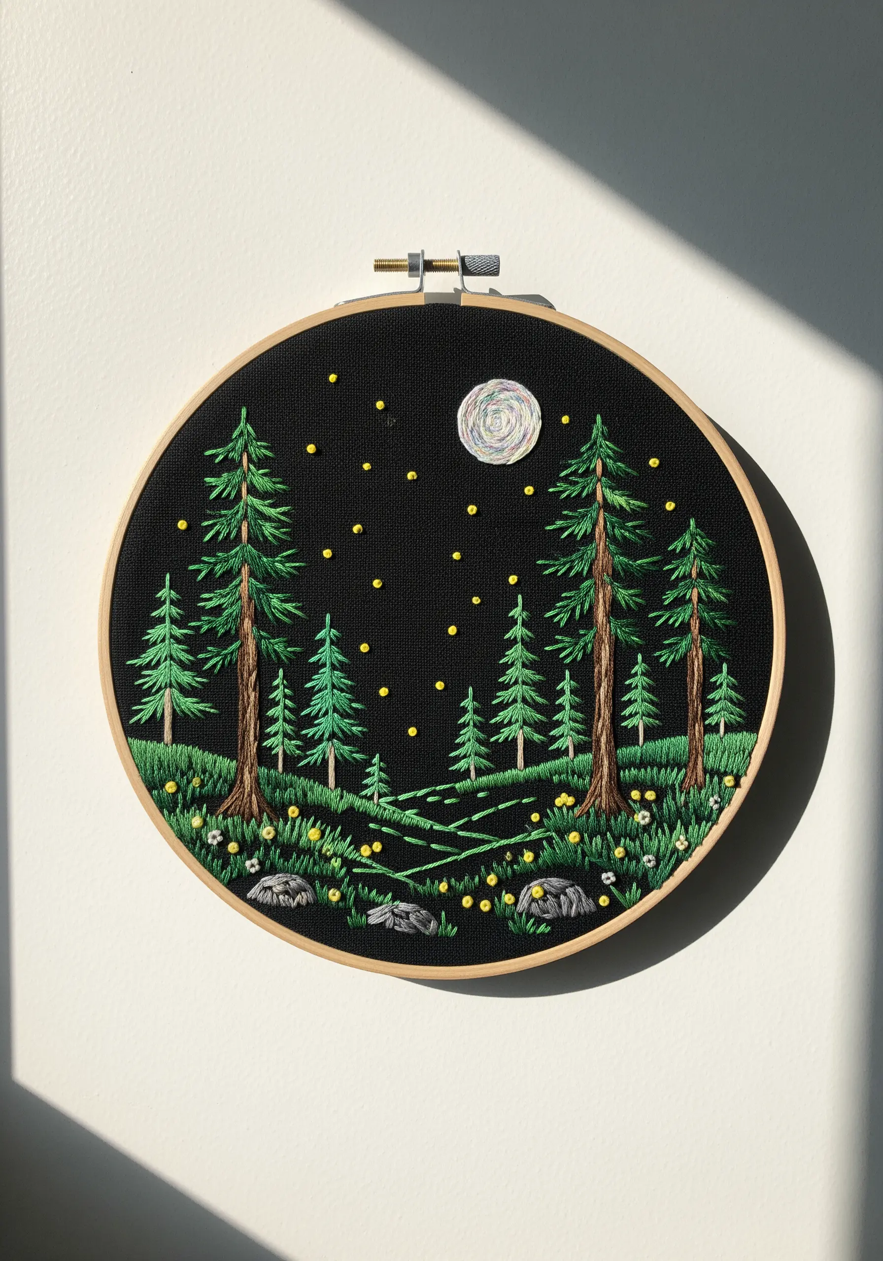 Embroidered night forest with a textured moon and yellow French knot fireflies.