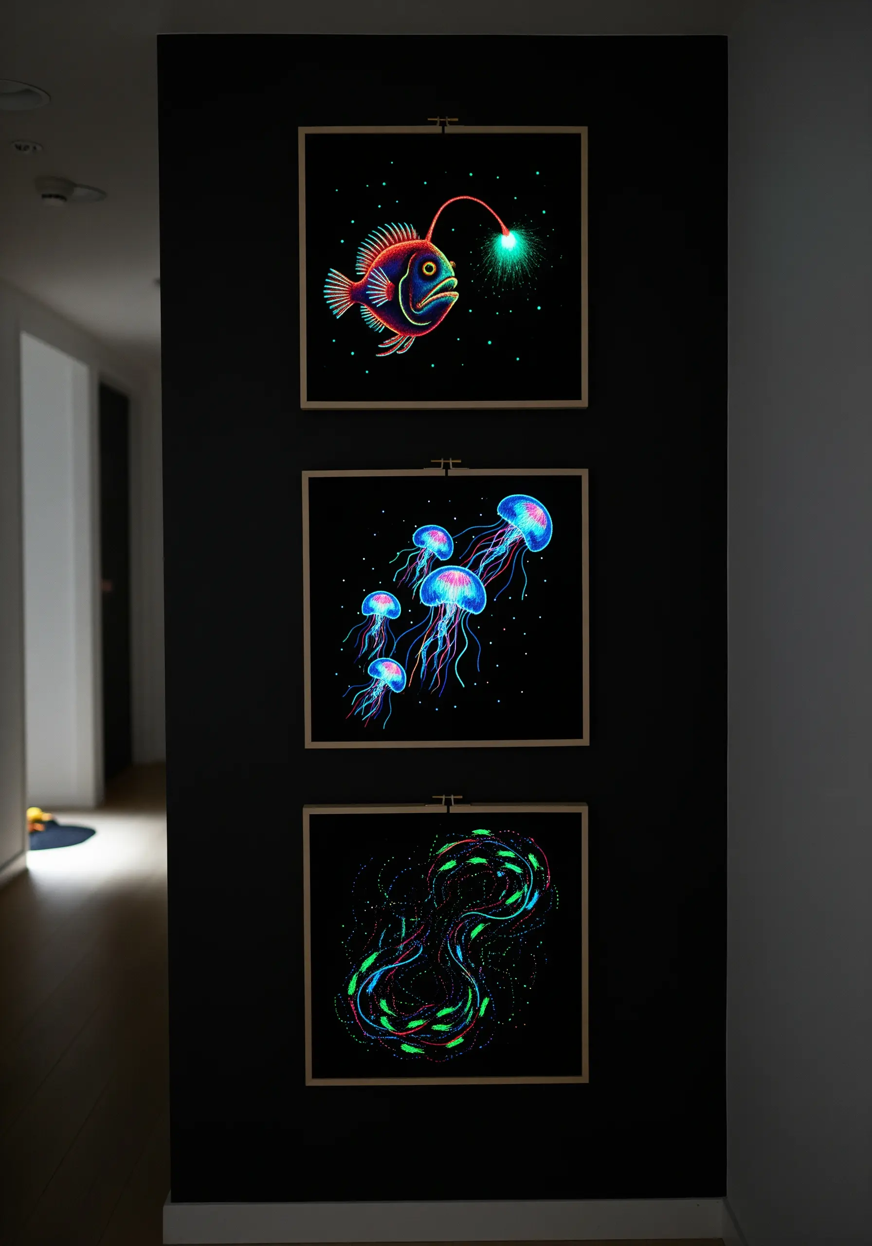 Three framed embroideries of bioluminescent sea creatures that glow in the dark.