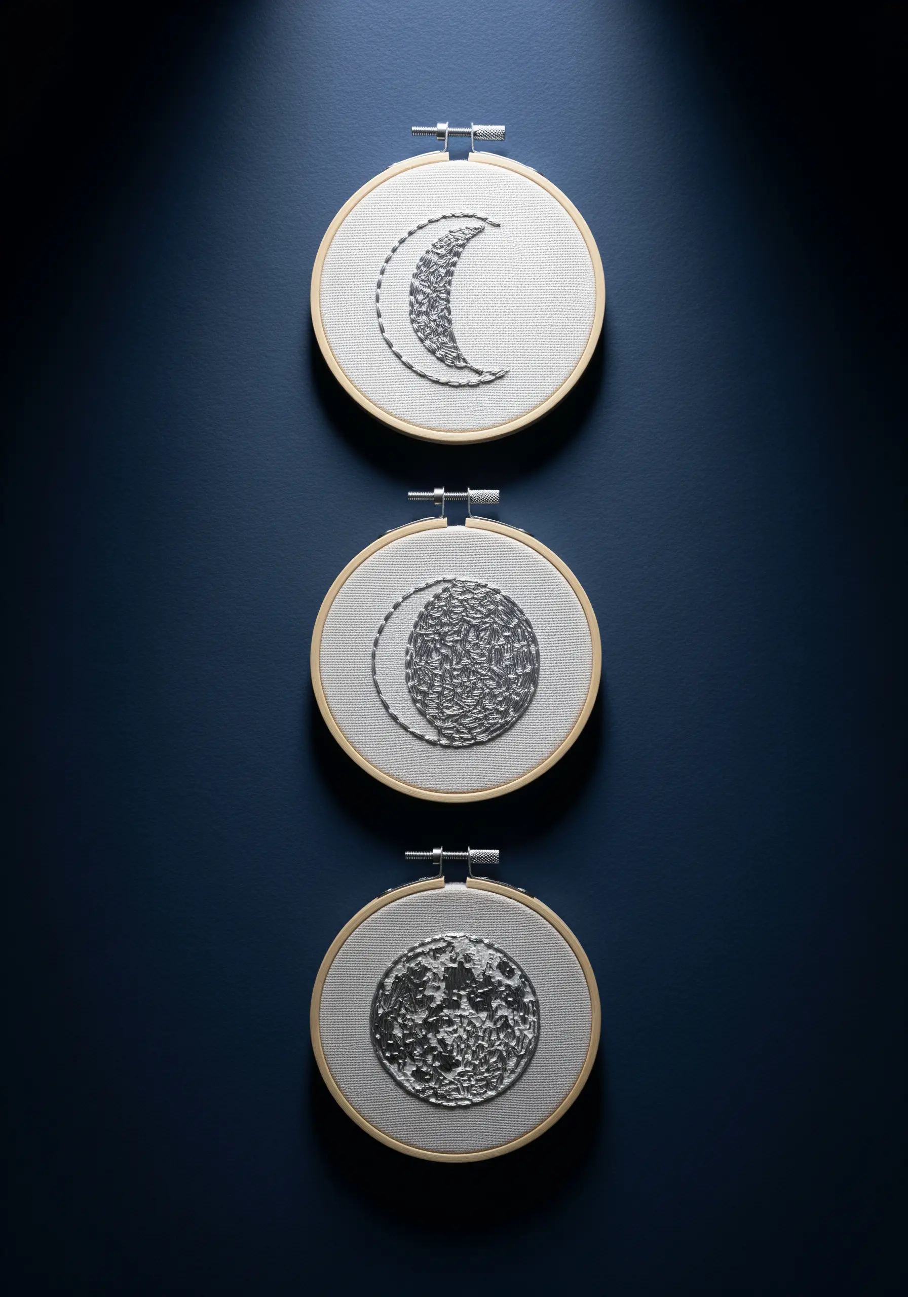 Three embroidery hoops showing moon phases with silver thread and abstract fill stitches.