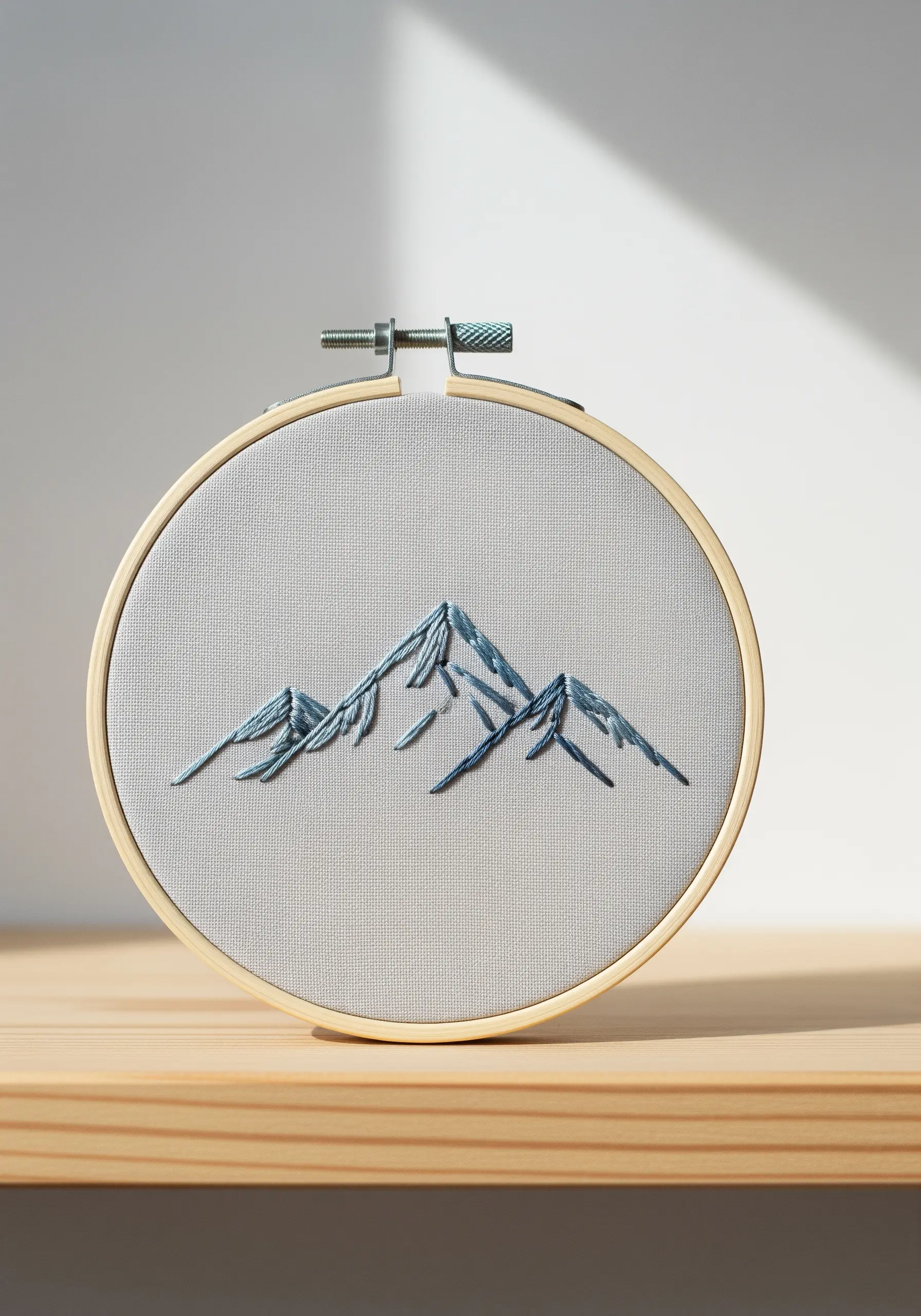 Minimalist mountain range stitched with layered straight stitches in shades of blue.