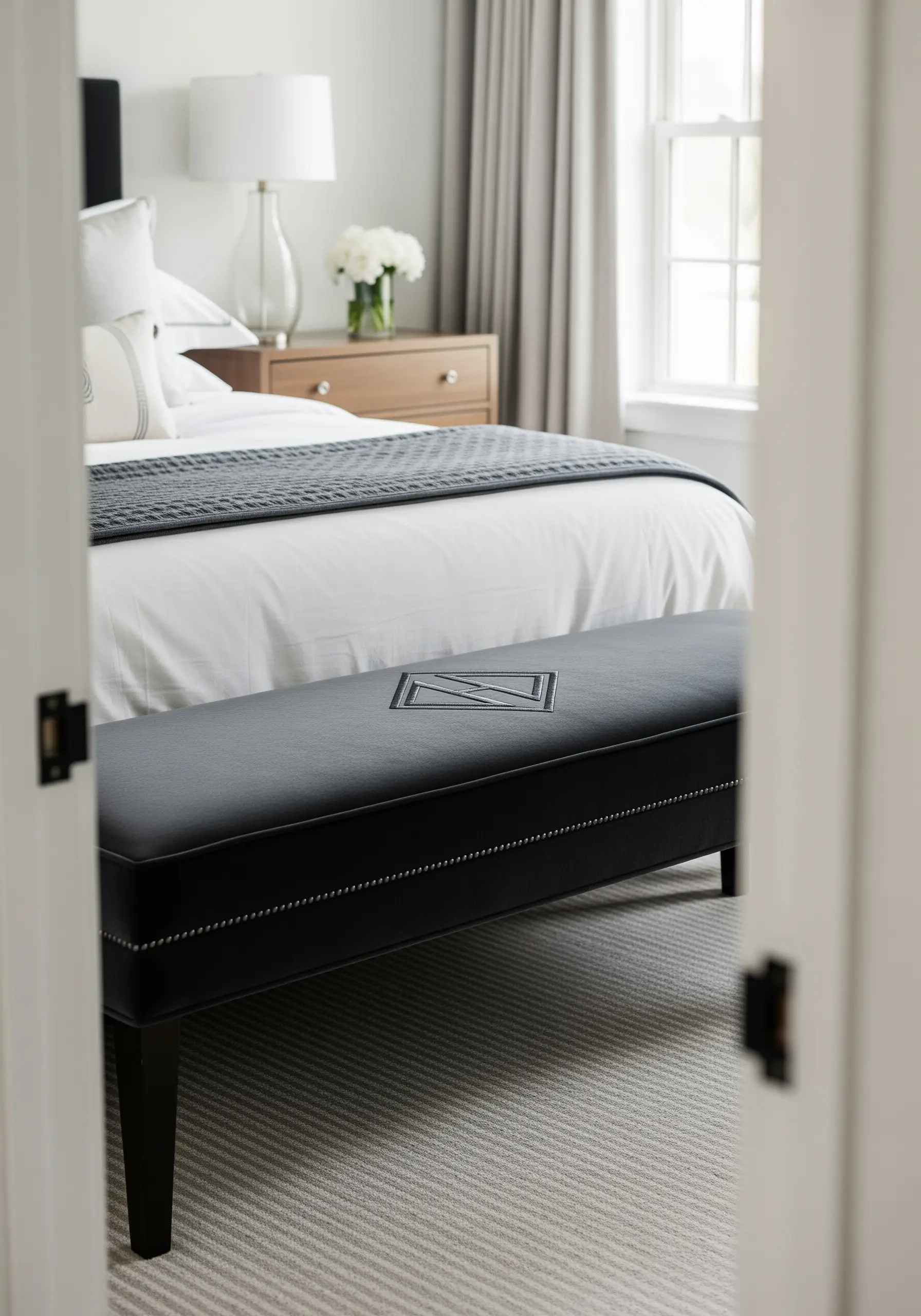 A diamond-shaped inset monogram on the surface of a black upholstered bench.