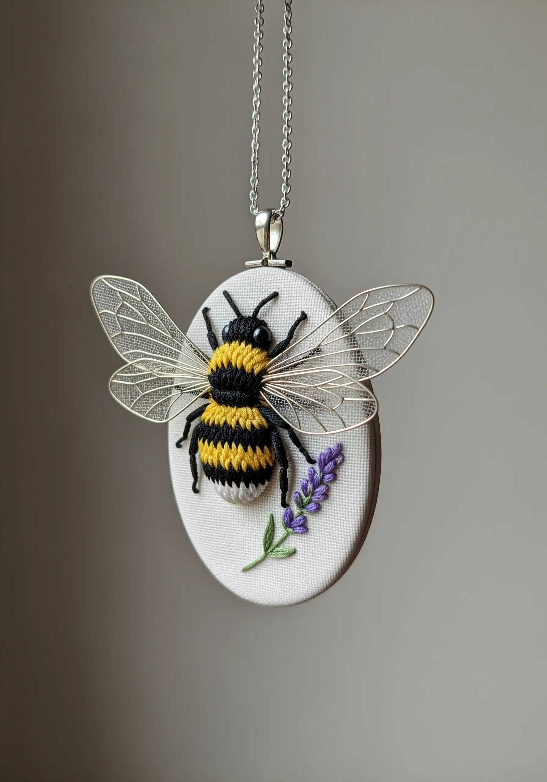 3D embroidered bee pendant with raised body and separate delicate metal wings.