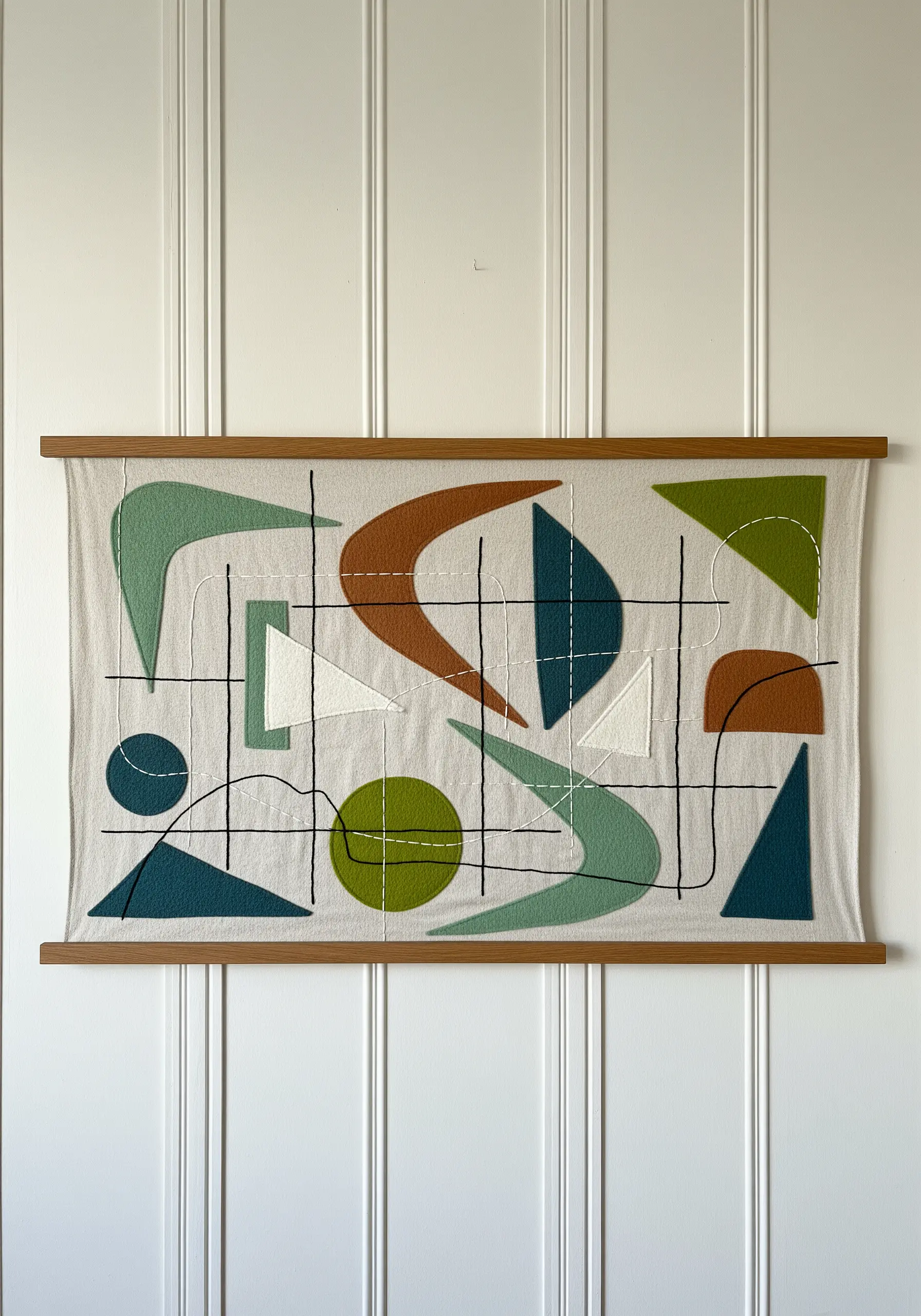 Mid-century modern textile wall art with abstract appliqué shapes and intersecting black stitched lines.