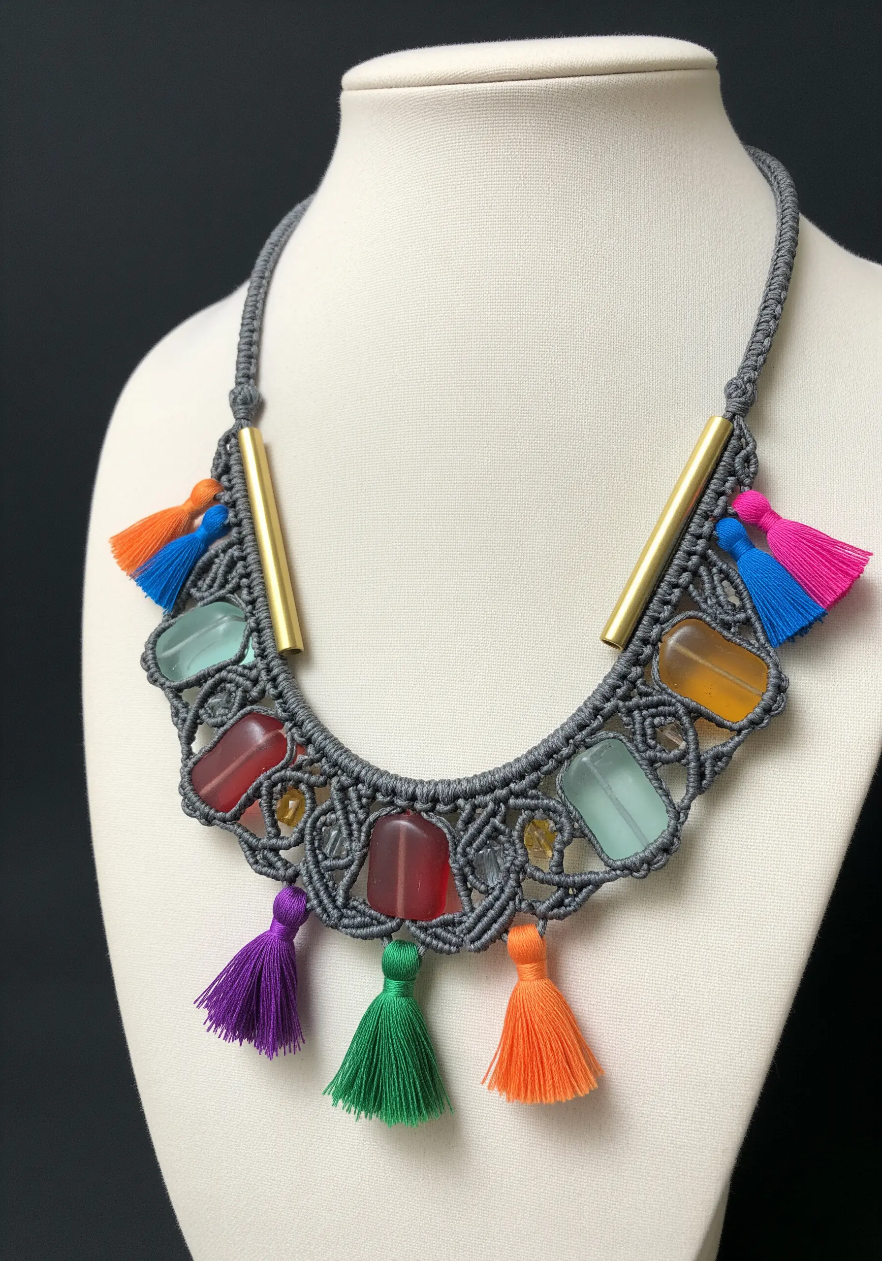 A detailed micro-macrame necklace in grey cord with colorful beads and small tassels.