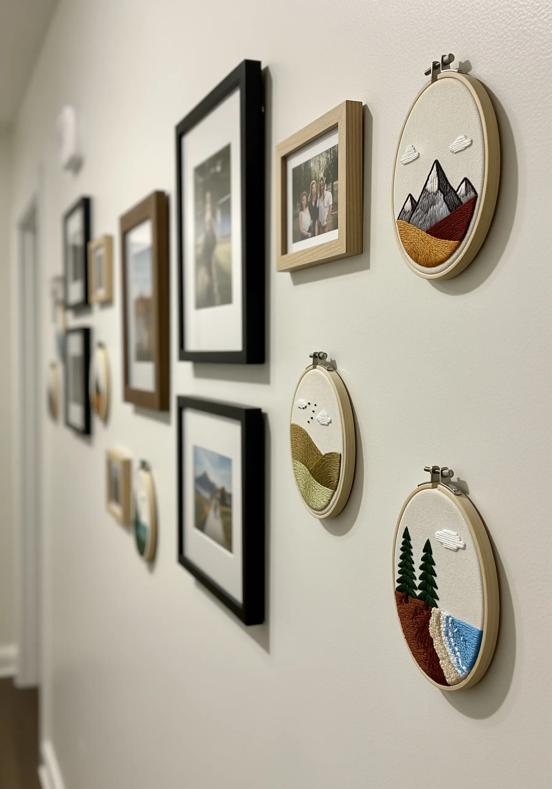 A gallery wall mixing framed photos with small, minimalist landscape embroidery hoops