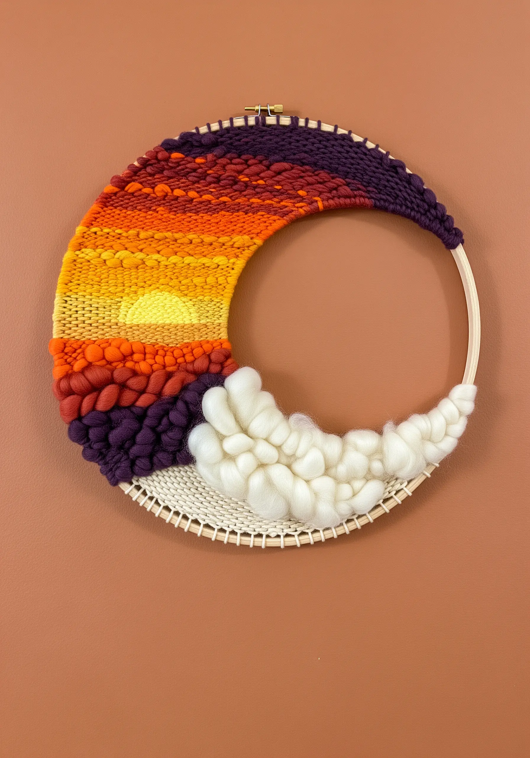 A circular weaving in a hoop depicting a sunset, with chunky white wool roving as clouds.