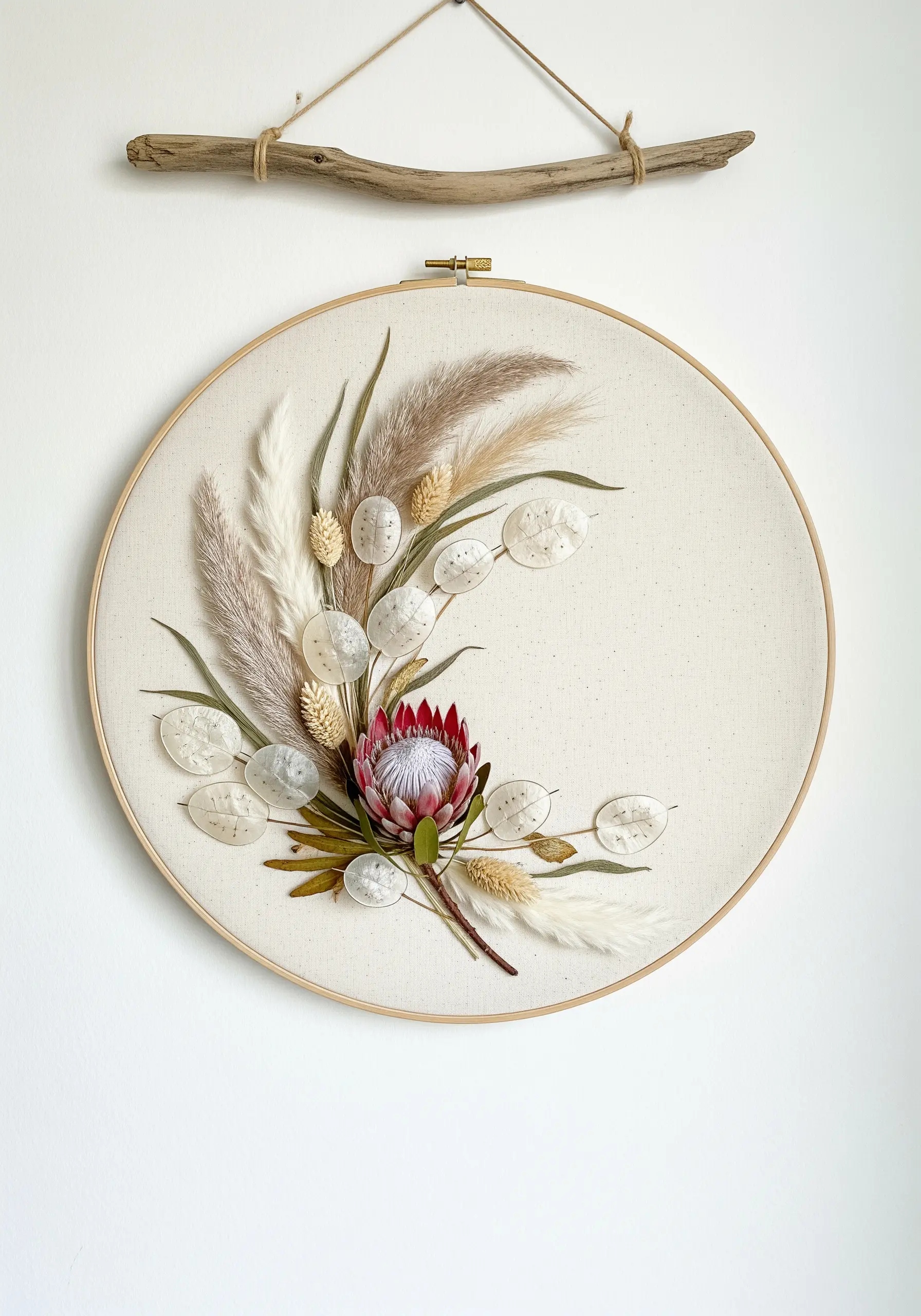 A mixed-media hoop with a bouquet of dried protea, lunaria, and grasses, accented with embroidery.