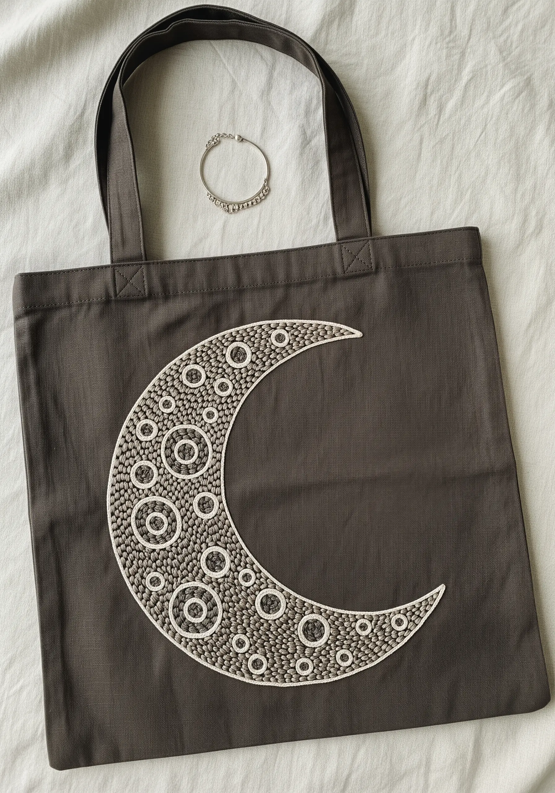 A crescent moon filled with a mosaic of French knots and seed stitches.