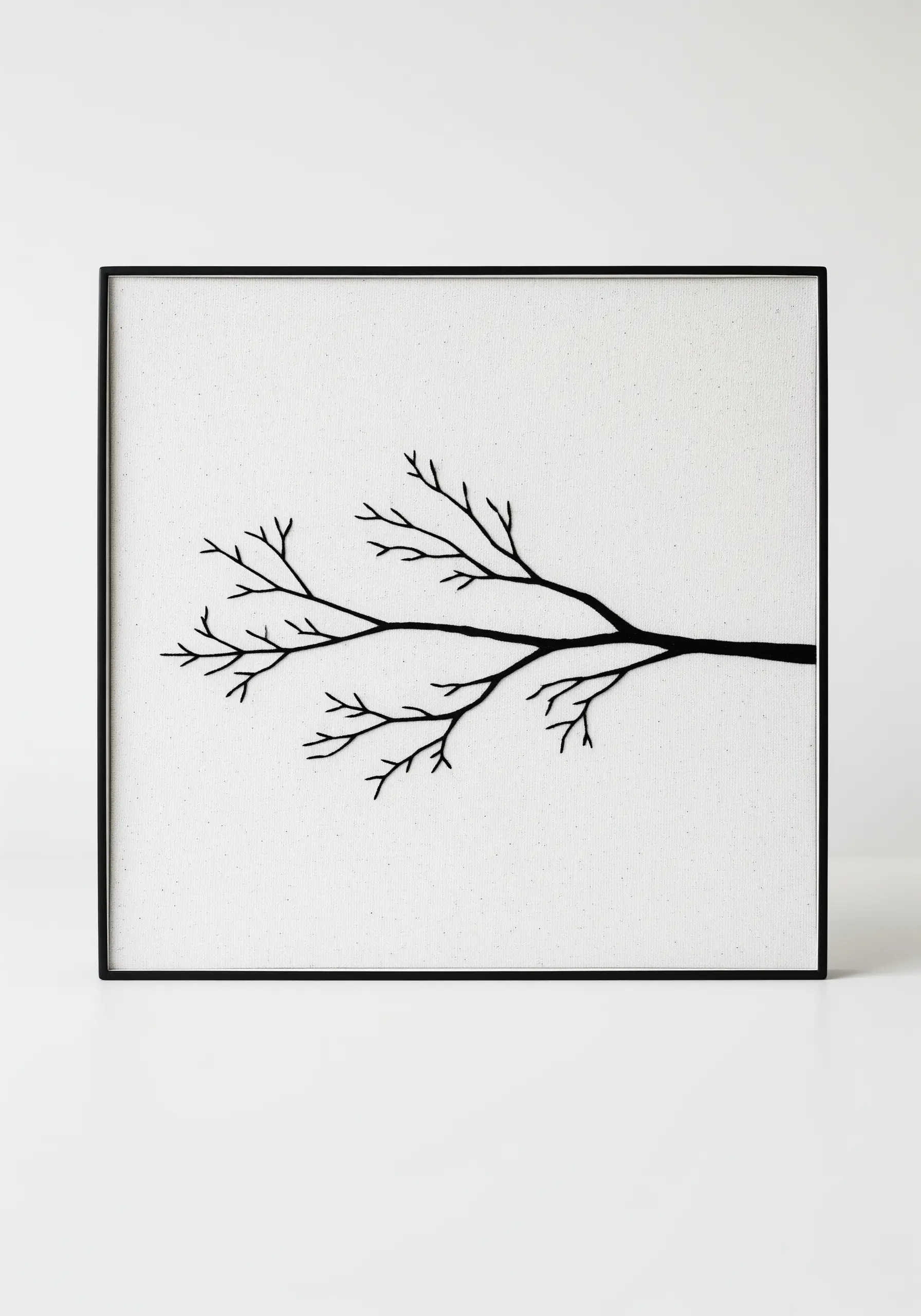 A black embroidered tree branch on white canvas, presented in a minimalist black frame.