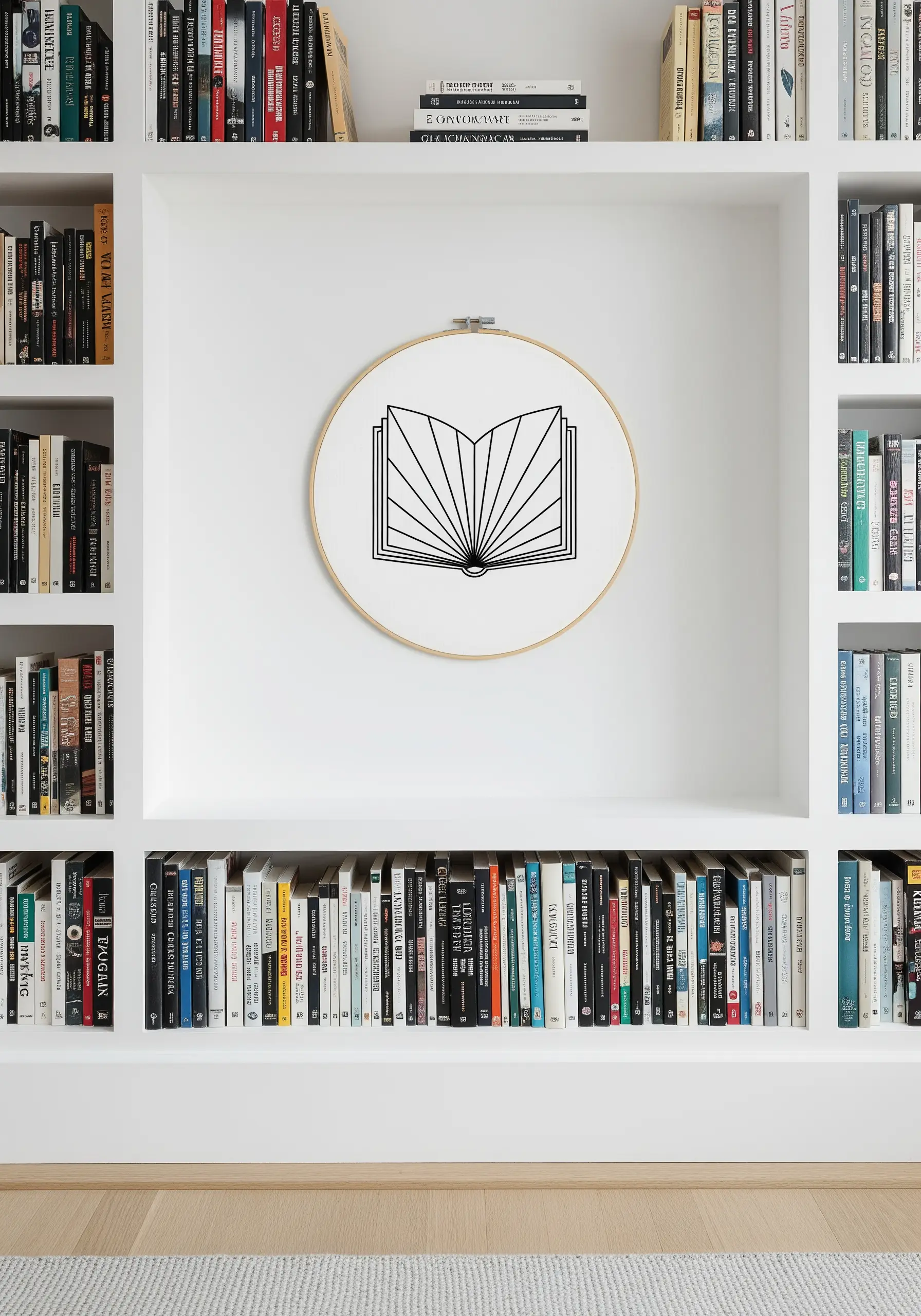 A single embroidery hoop with a black line-art illustration of an open book on a bookshelf.