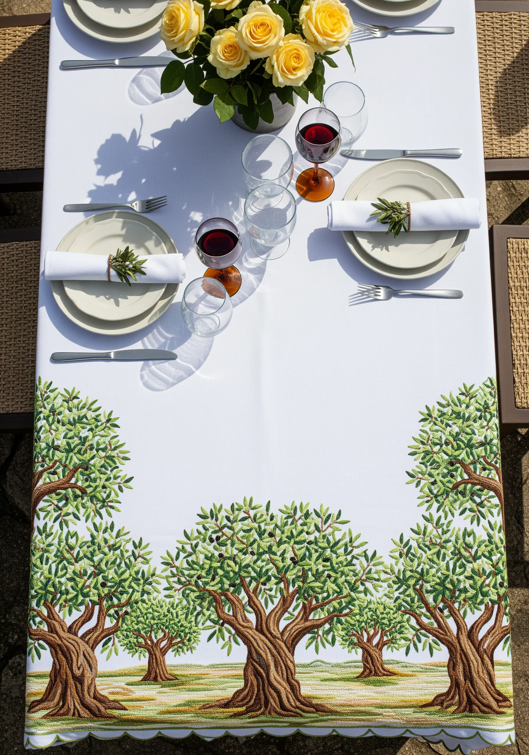 A detailed embroidered olive grove scene on the border of a white tablecloth.