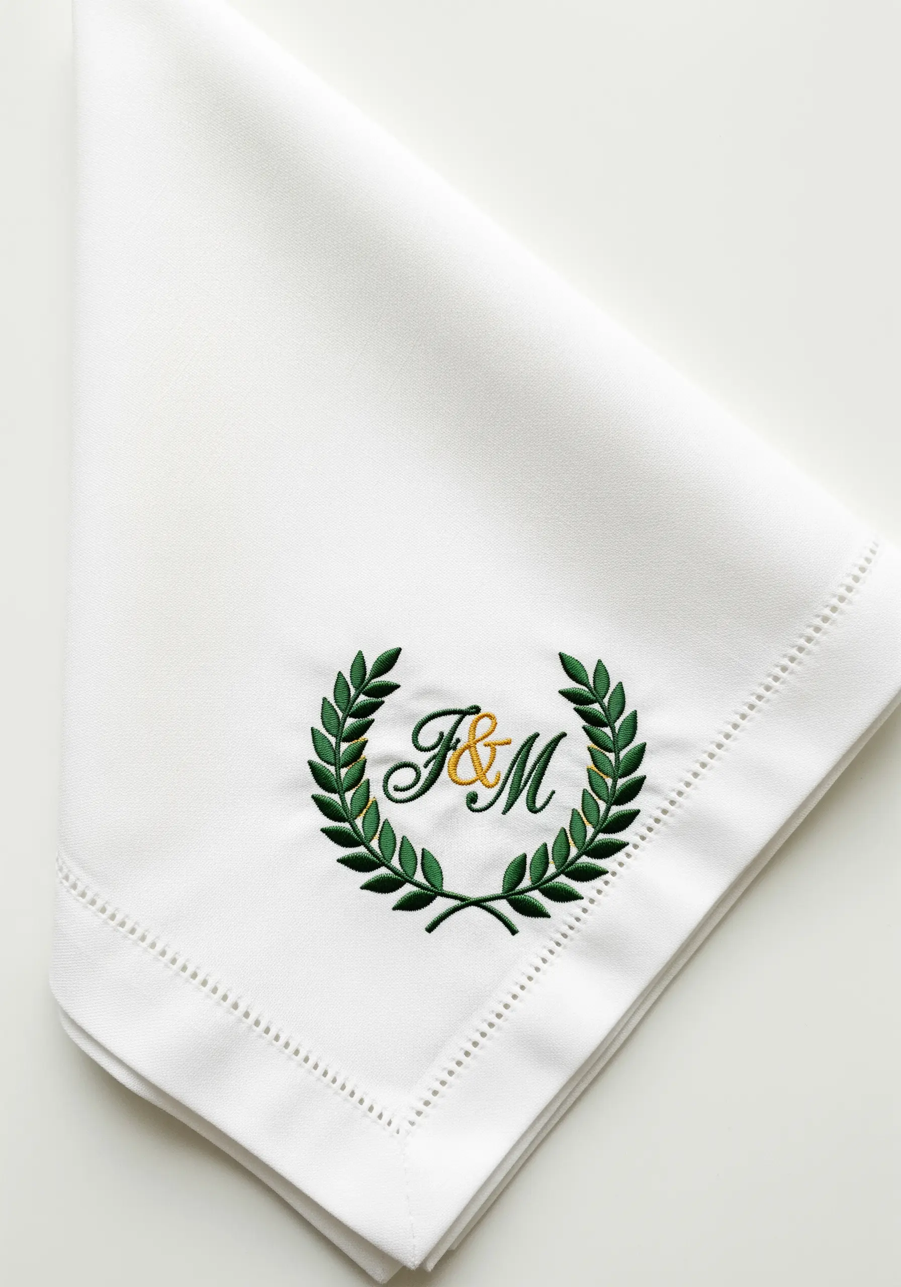 Classic green laurel wreath surrounding an F&M monogram on a white napkin.