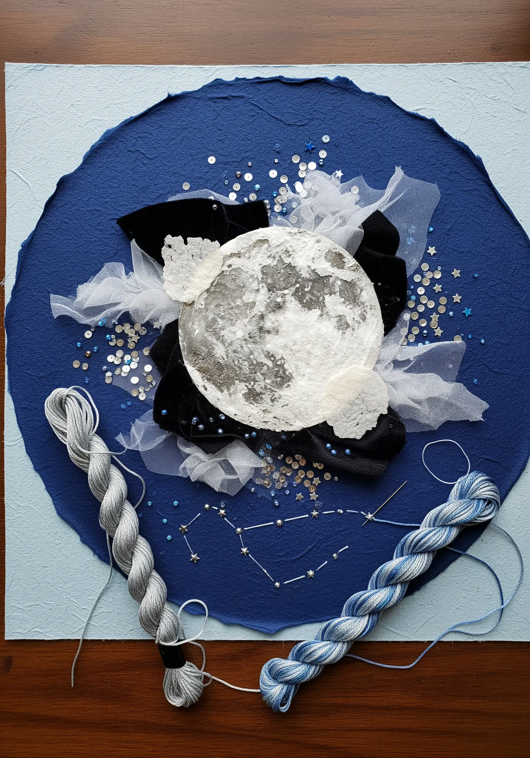 Mixed-media collage of a moon with velvet, tulle, sequins, and embroidered constellation.