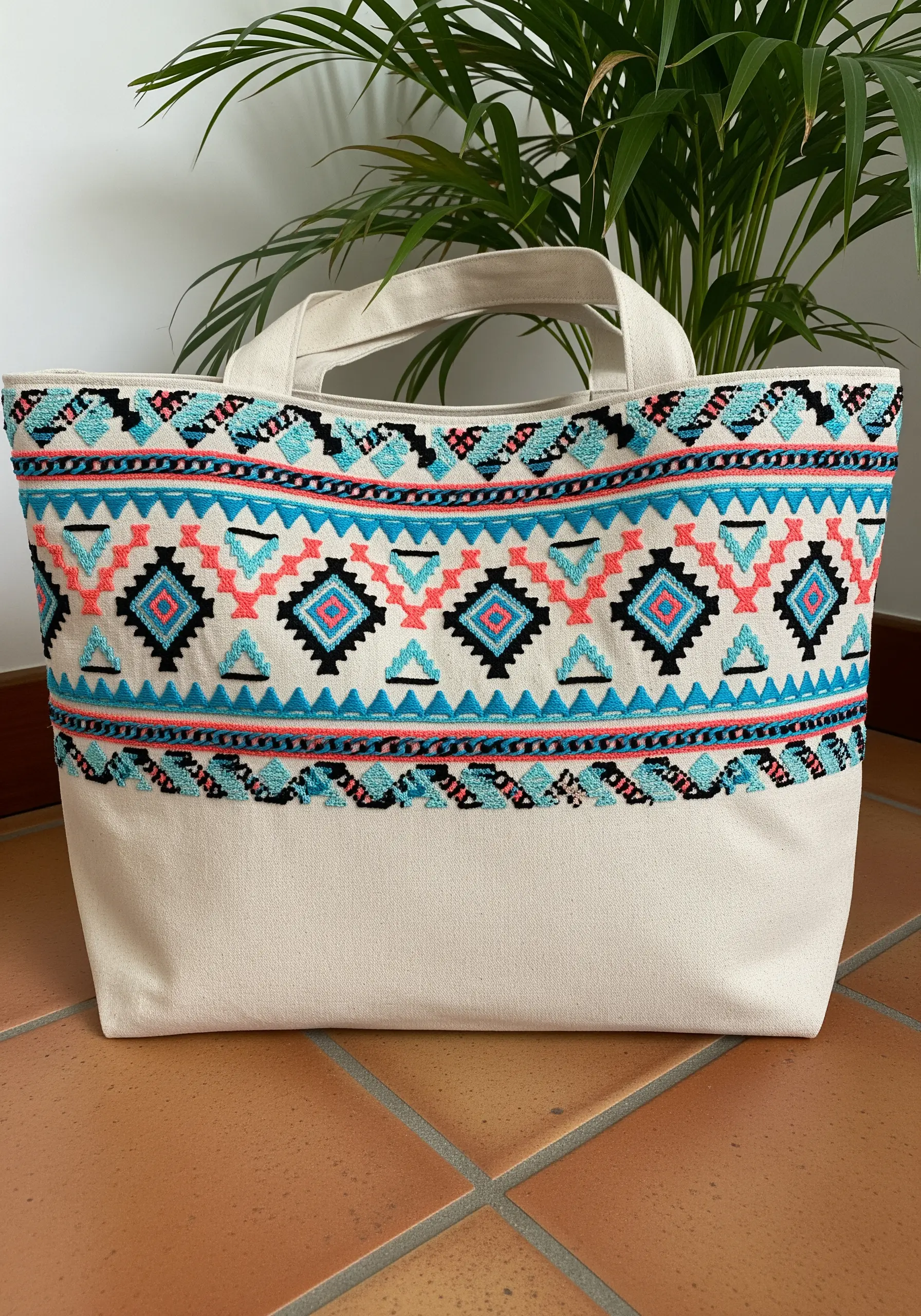A vibrant, wide band of Southwestern-inspired geometric embroidery on a canvas tote.