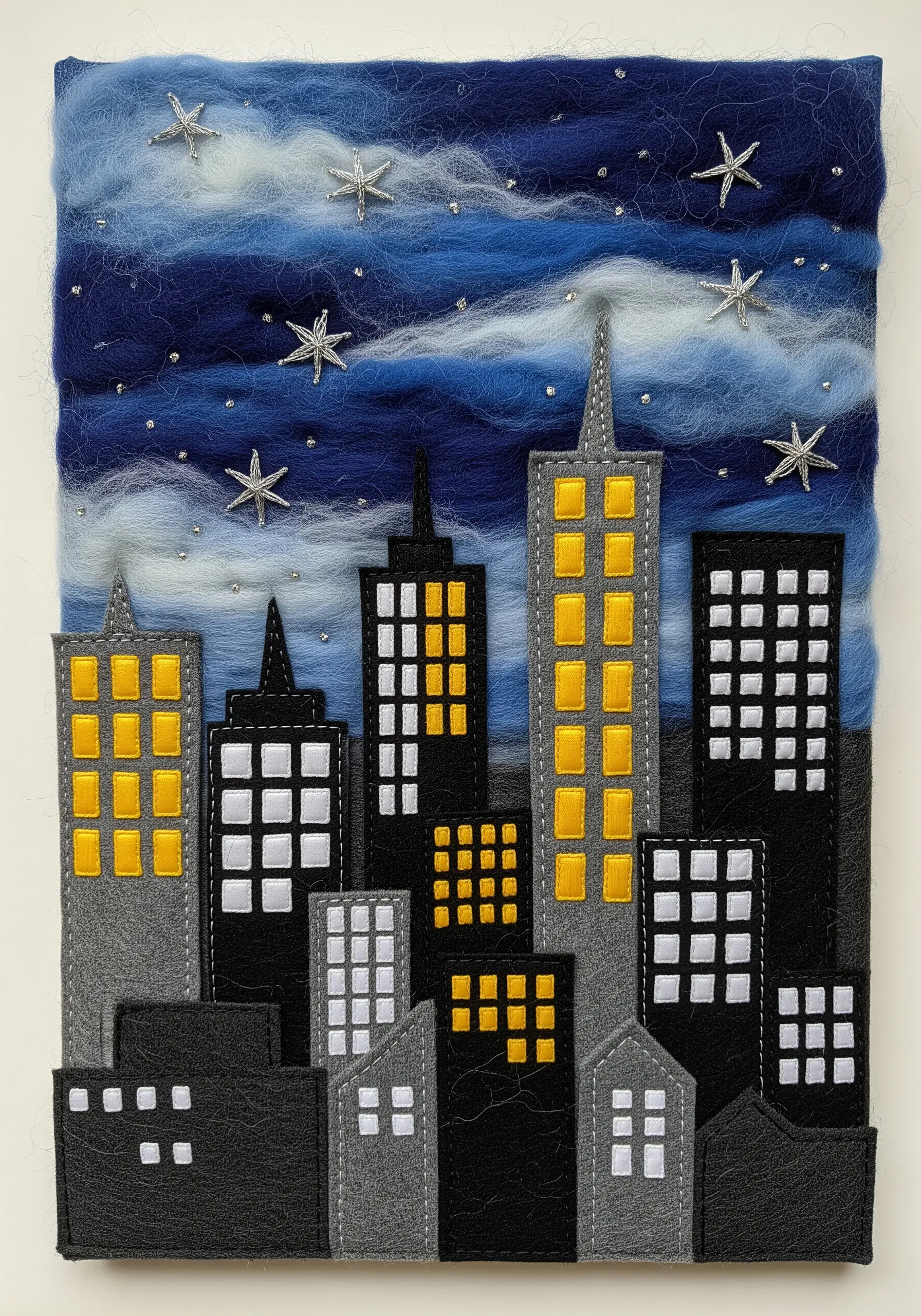 A cityscape at night made with layered felt appliqué, embroidery, and a needle-felted sky.