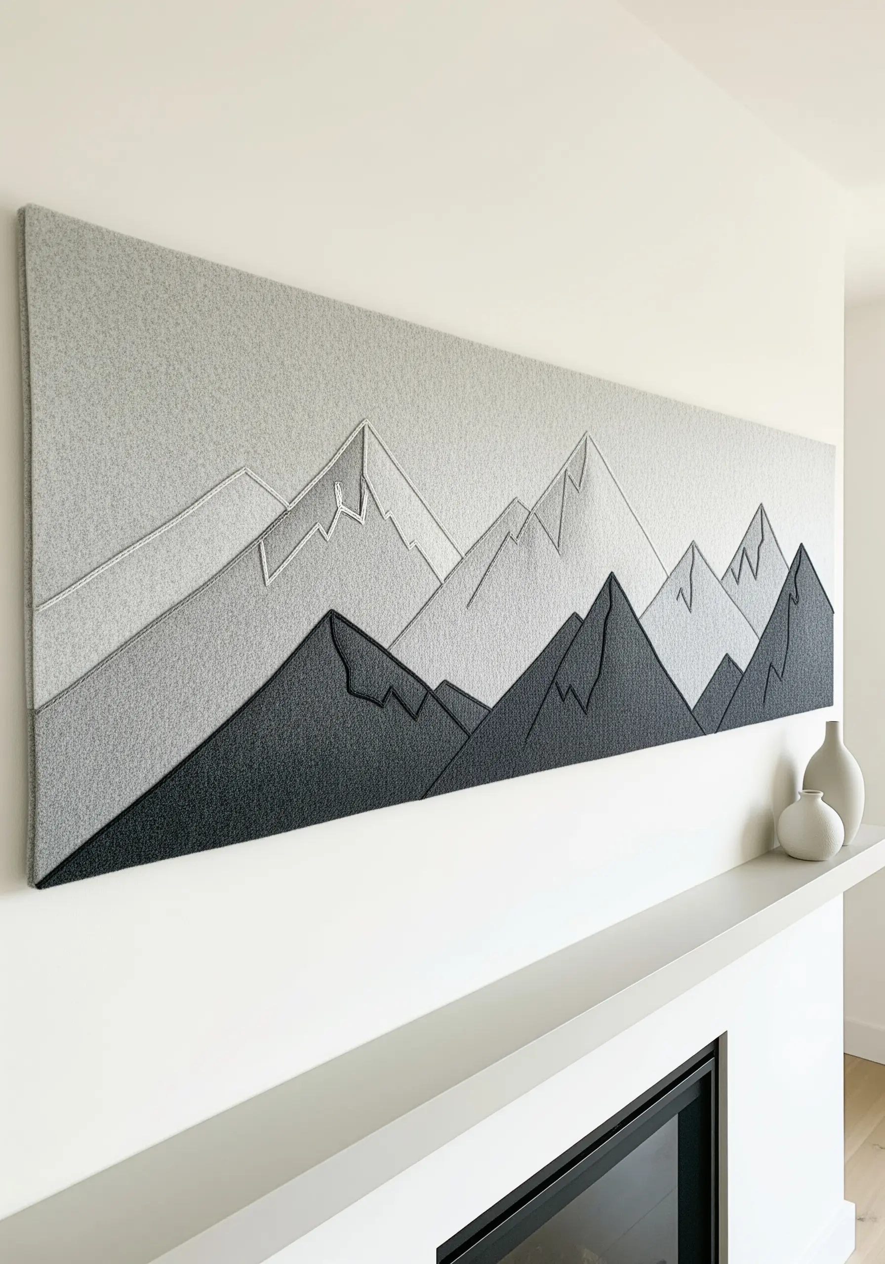 Monochrome mountain landscape made from layered felt with simple line stitching.