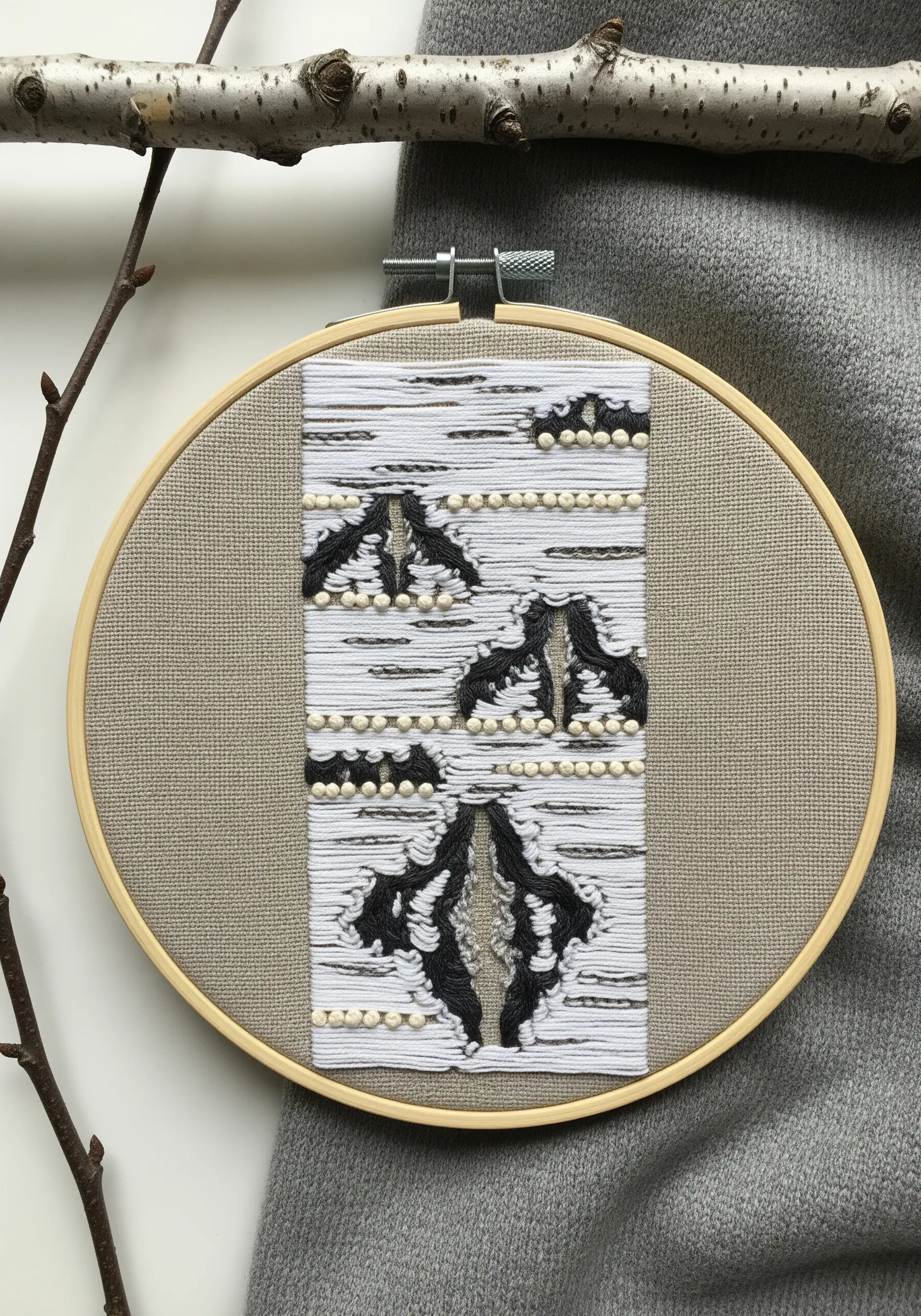 Abstract birch bark embroidery with white satin stitch, black yarn, and dimensional French knots.