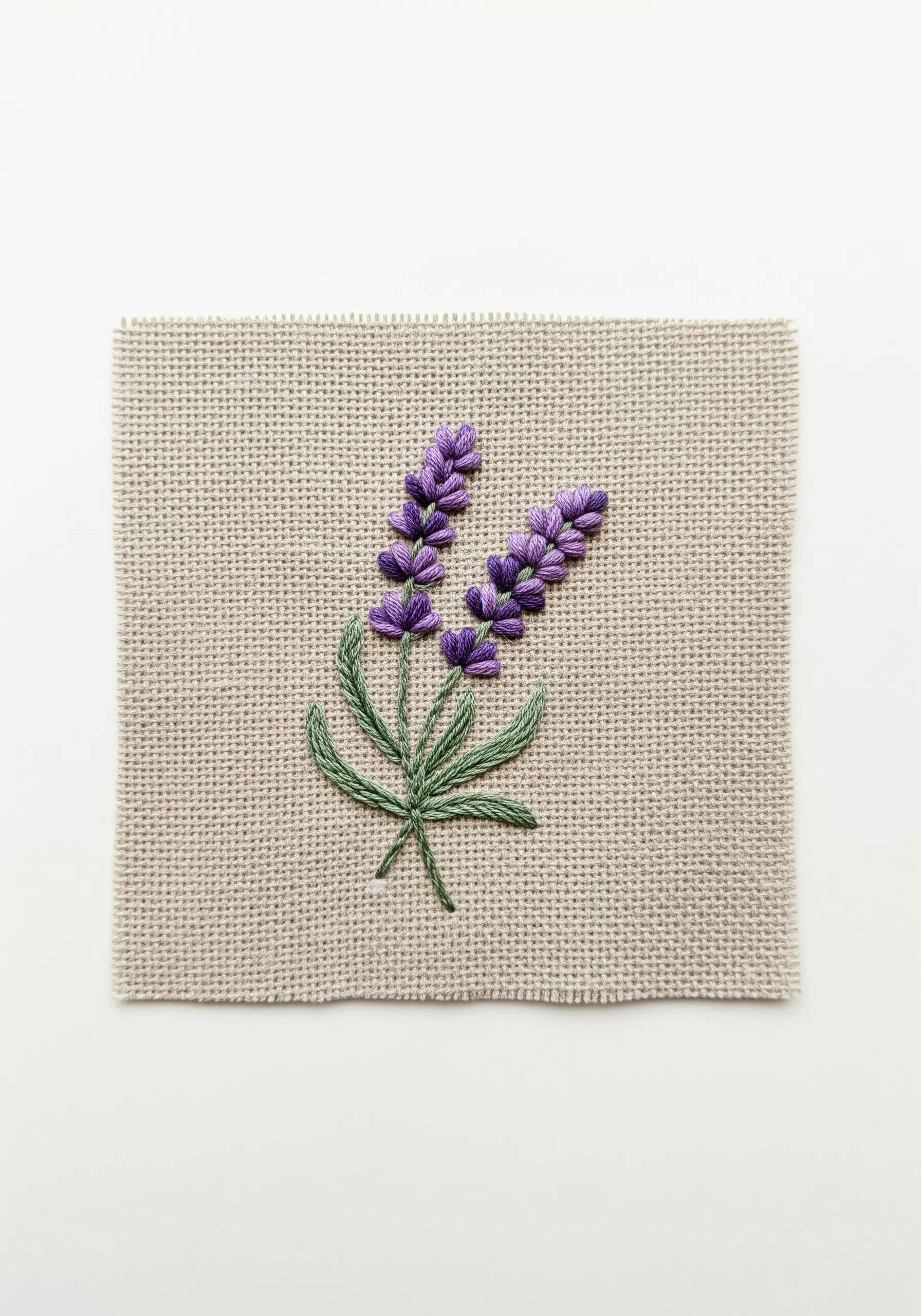 Lavender sprigs embroidered on burlap with textured purple satin stitch and green stems.