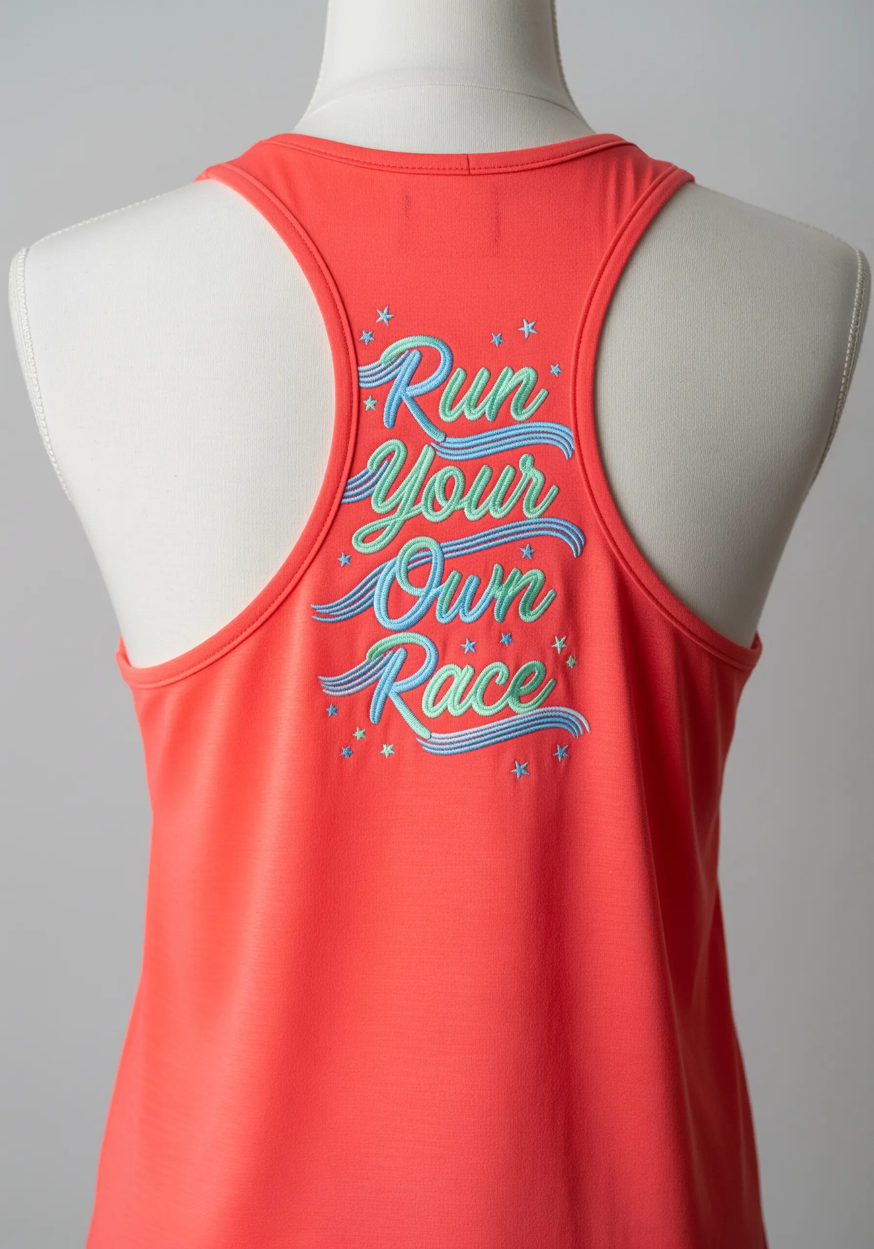 “Run Your Own Race” in multi-colored retro script on the back of a coral tank top.