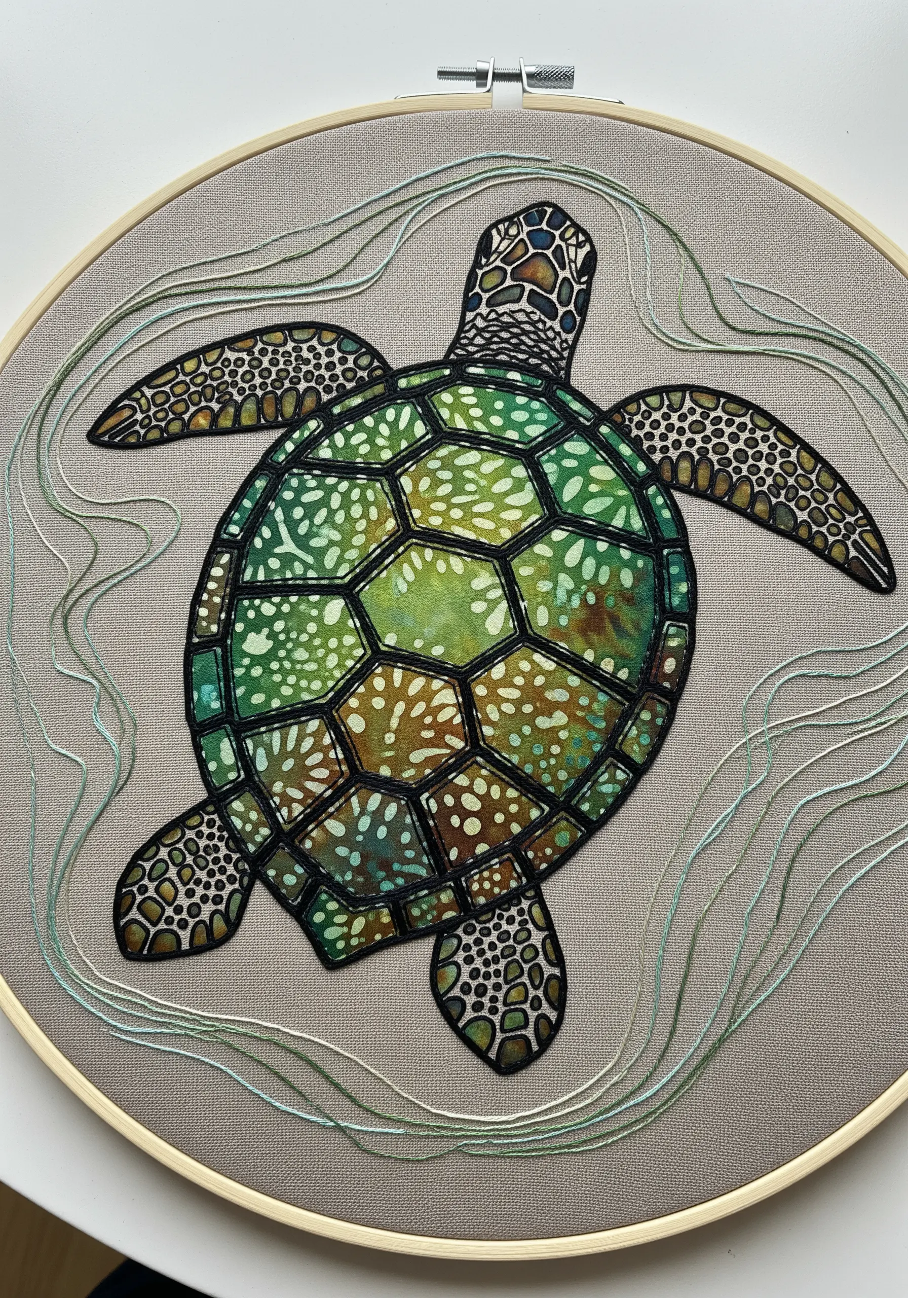 A sea turtle made from green and brown batik fabric appliqué, outlined with black thread.