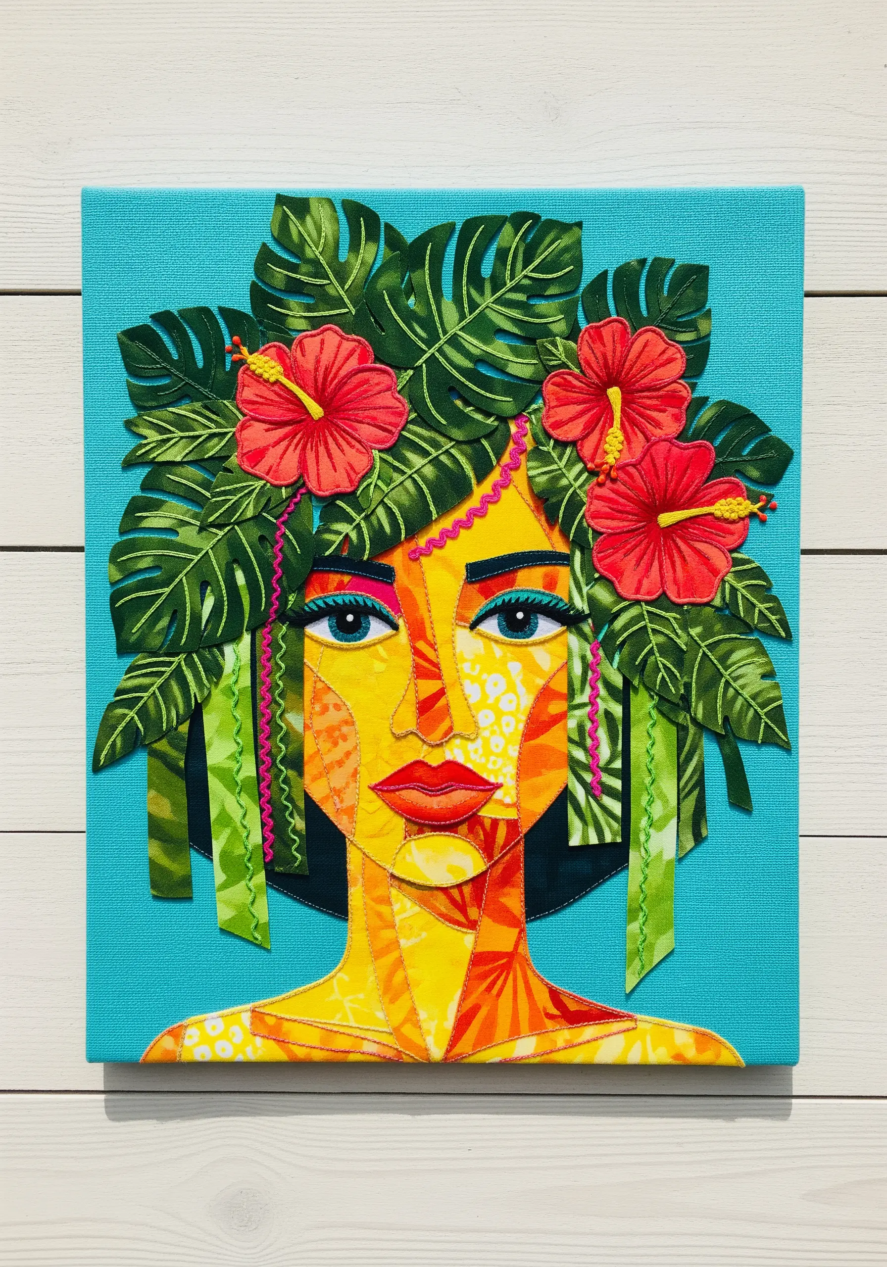 Vibrant portrait made from patterned fabric collage, outlined with simple stitching.