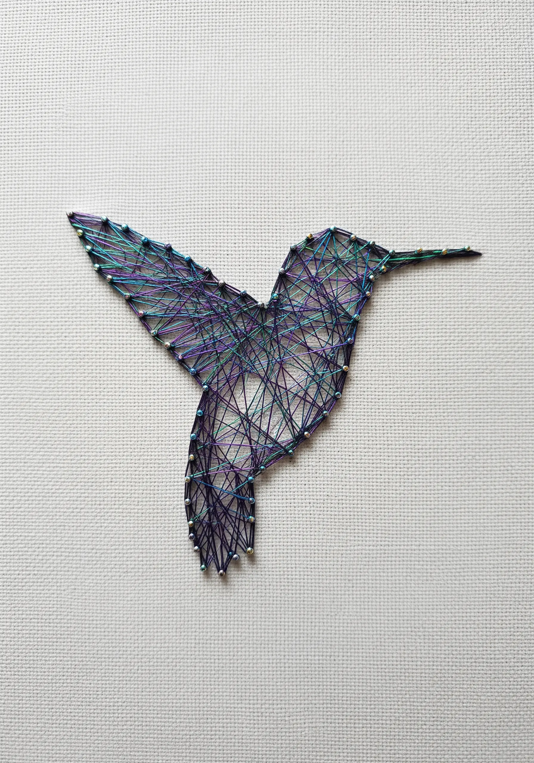 Hummingbird silhouette embroidered with variegated purple, blue, and green thread.
