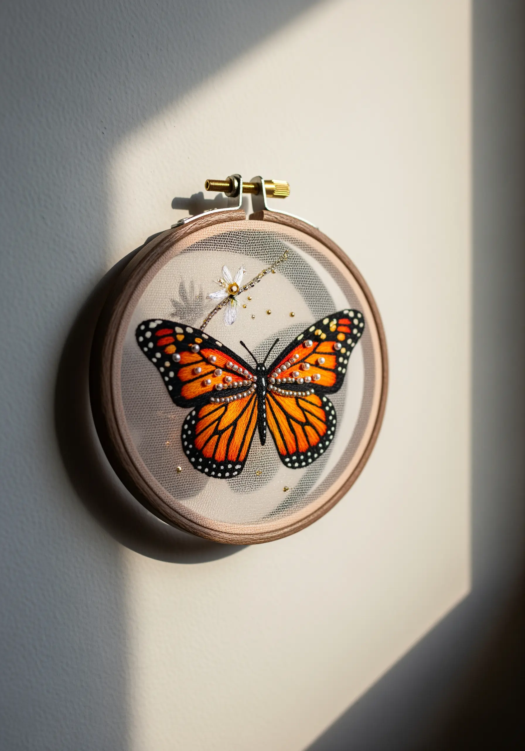 An embroidered monarch butterfly on sheer tulle fabric stretched in a wooden hoop.