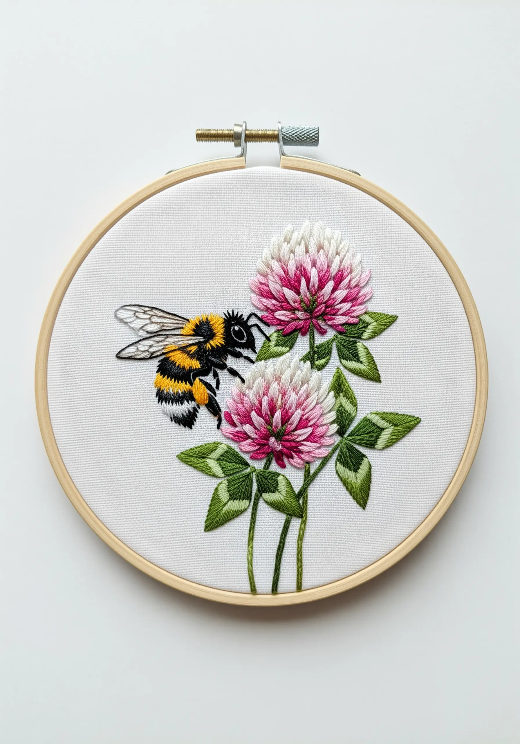 Realistically embroidered bee on a pink and white clover flower.