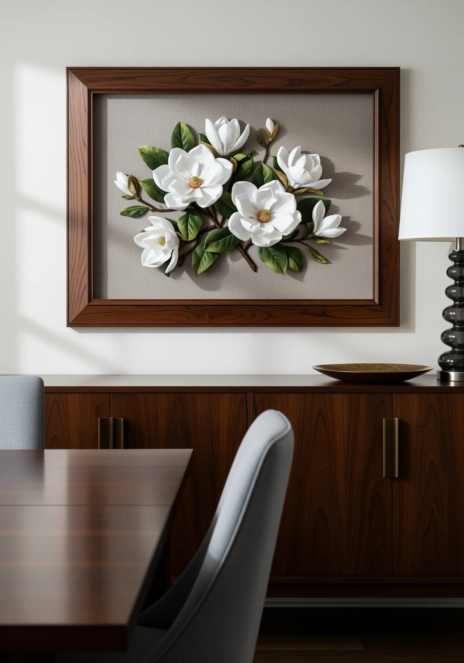 Framed 3D embroidery of white magnolia flowers with raised petals and leaves on gray fabric.