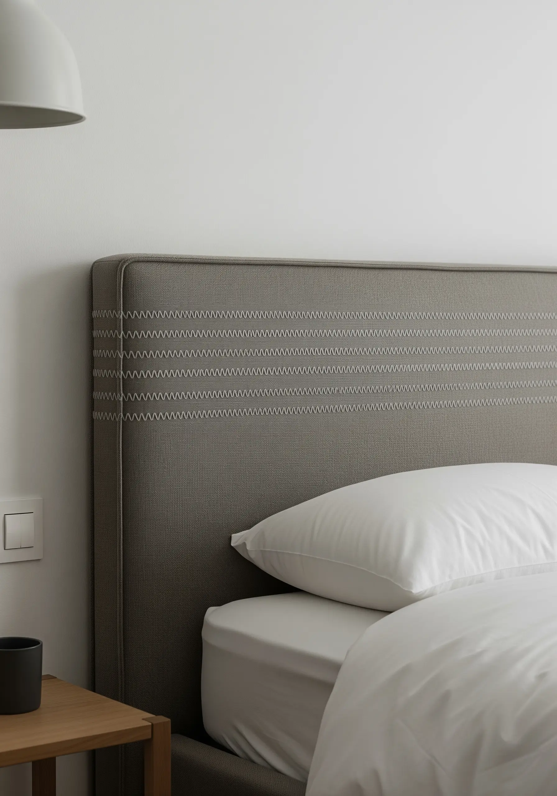 Horizontal bands of white decorative stitching on a gray upholstered headboard.