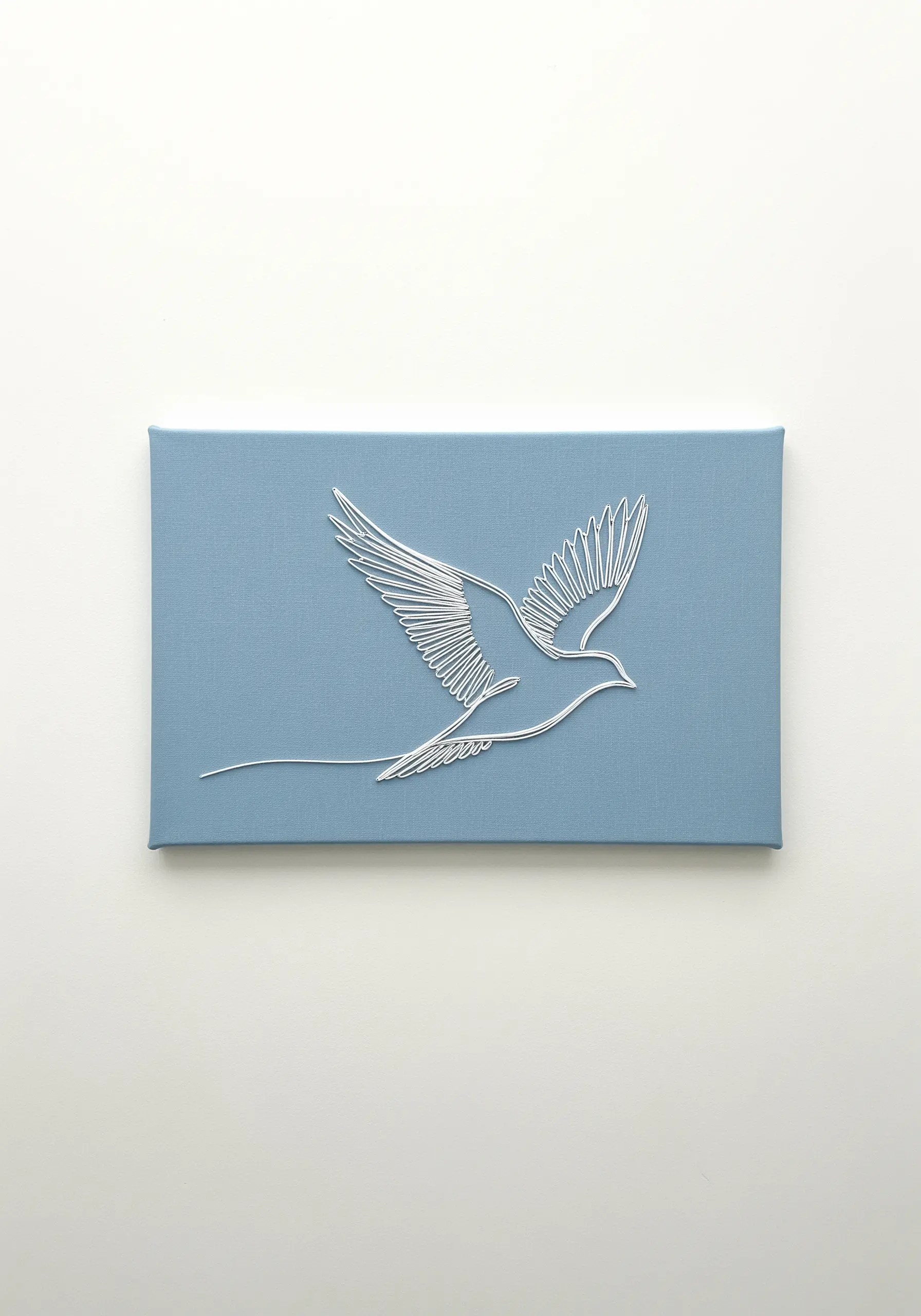 A flying dove embroidered in silver thread, with wings created from long satin stitches.