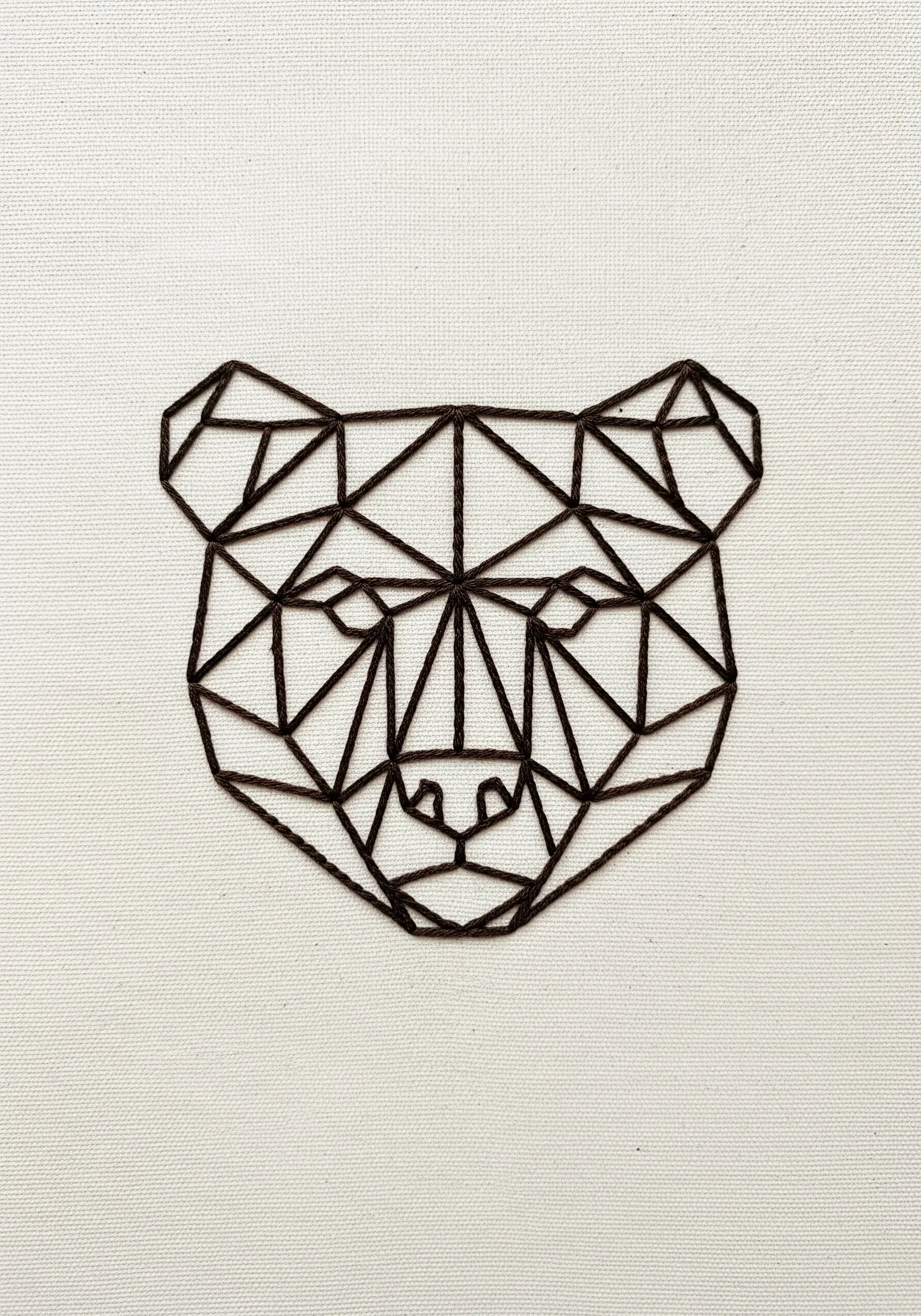 Geometric low-poly bear head embroidery using straight dark lines