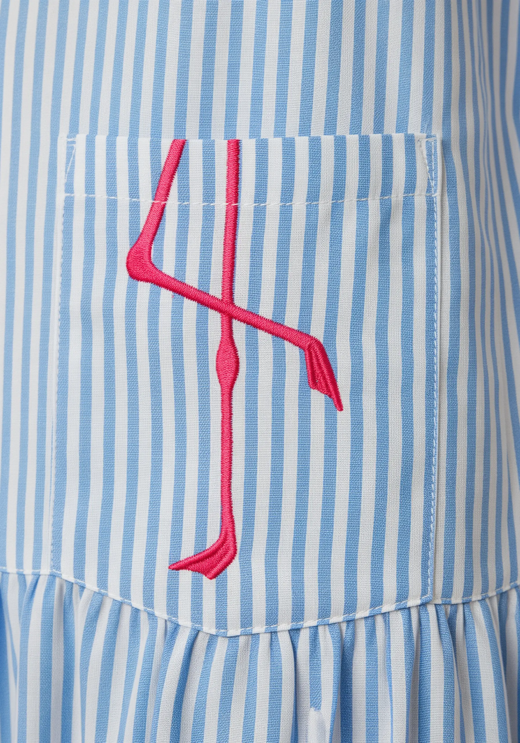 An abstract, geometric hot pink flamingo embroidered on a striped dress pocket.