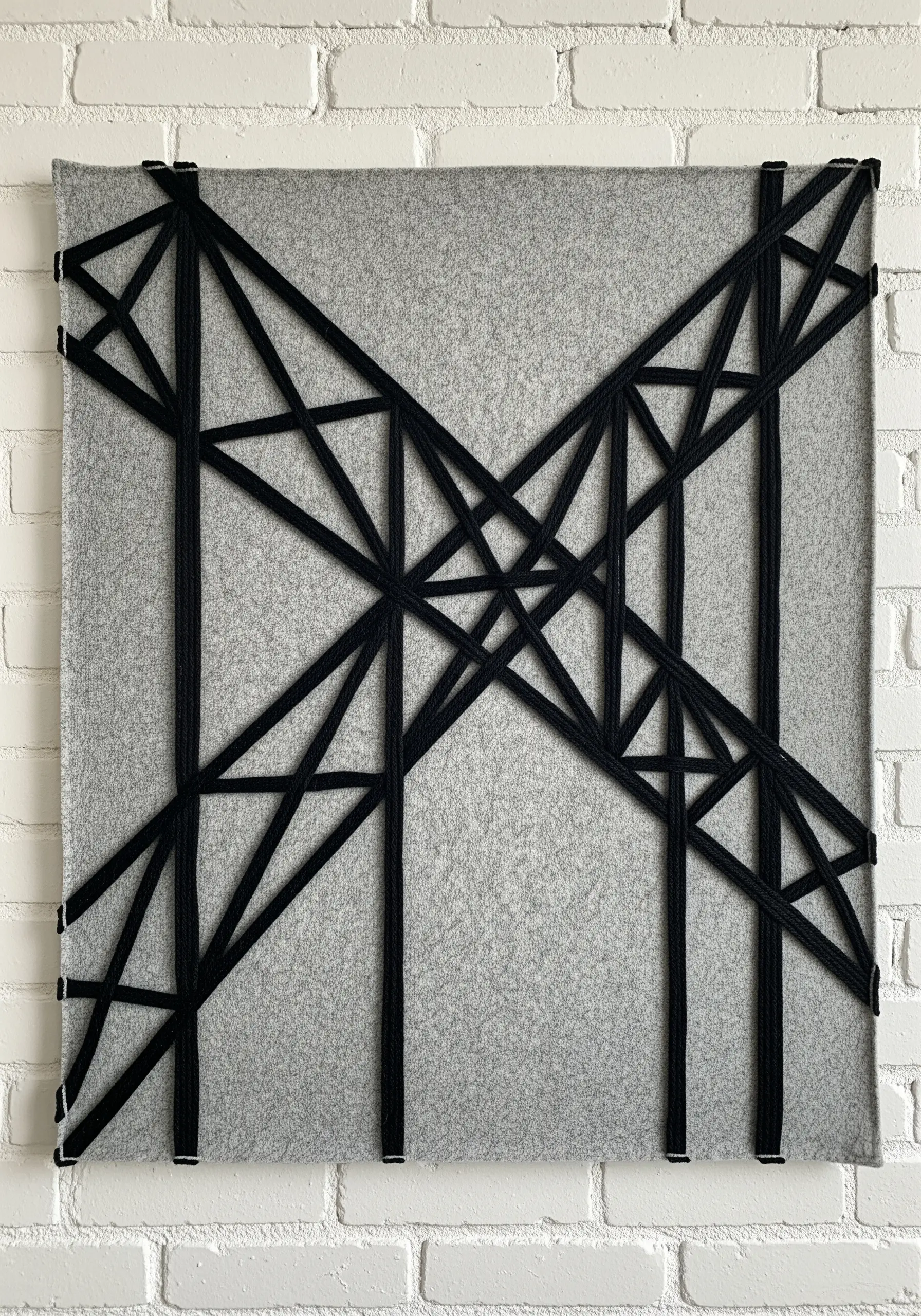 Large-scale abstract wall art made with thick black yarn wrapped around a grey felt board.