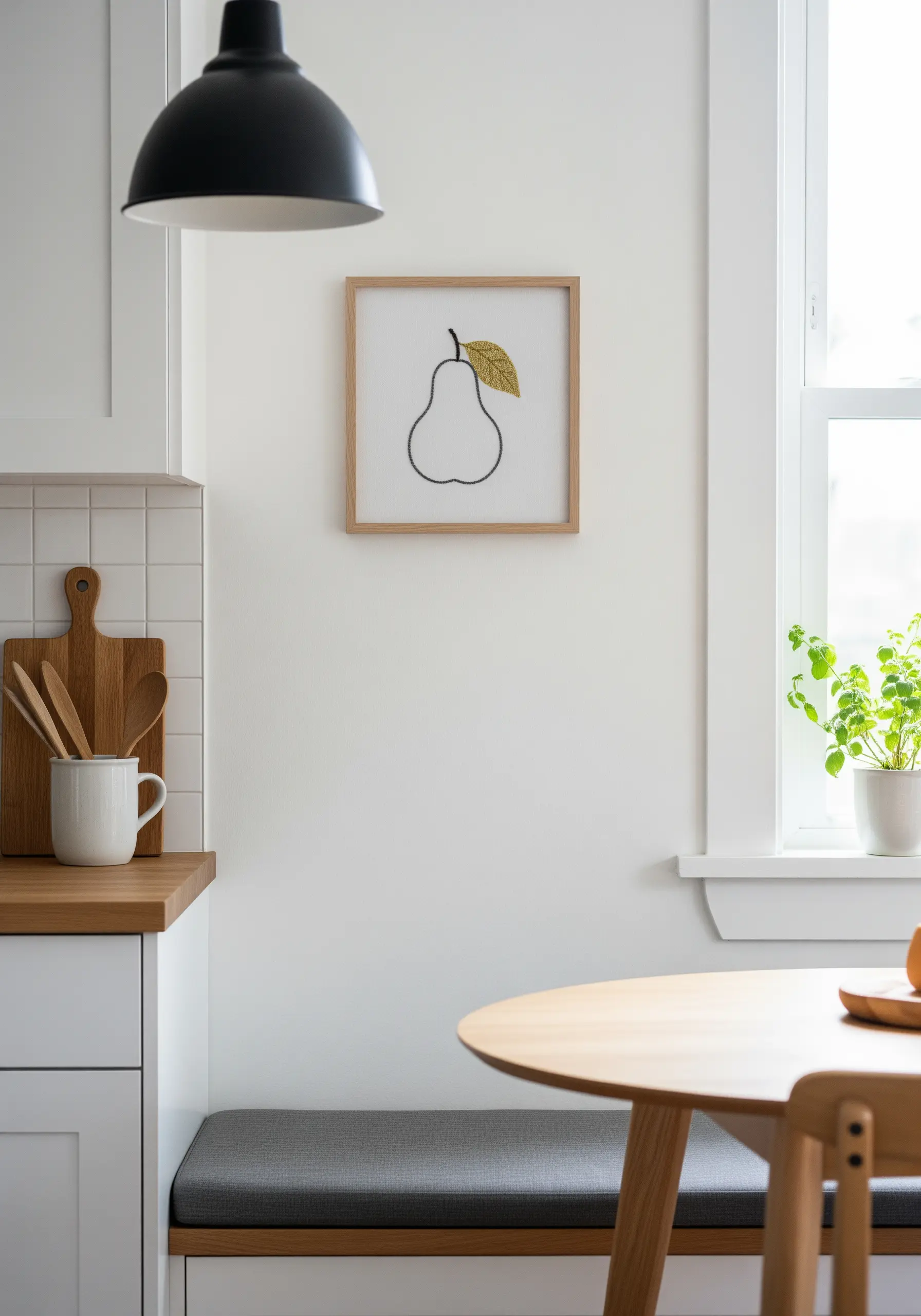 A framed embroidery of a pear outlined in black, with its single leaf filled in with gold thread.