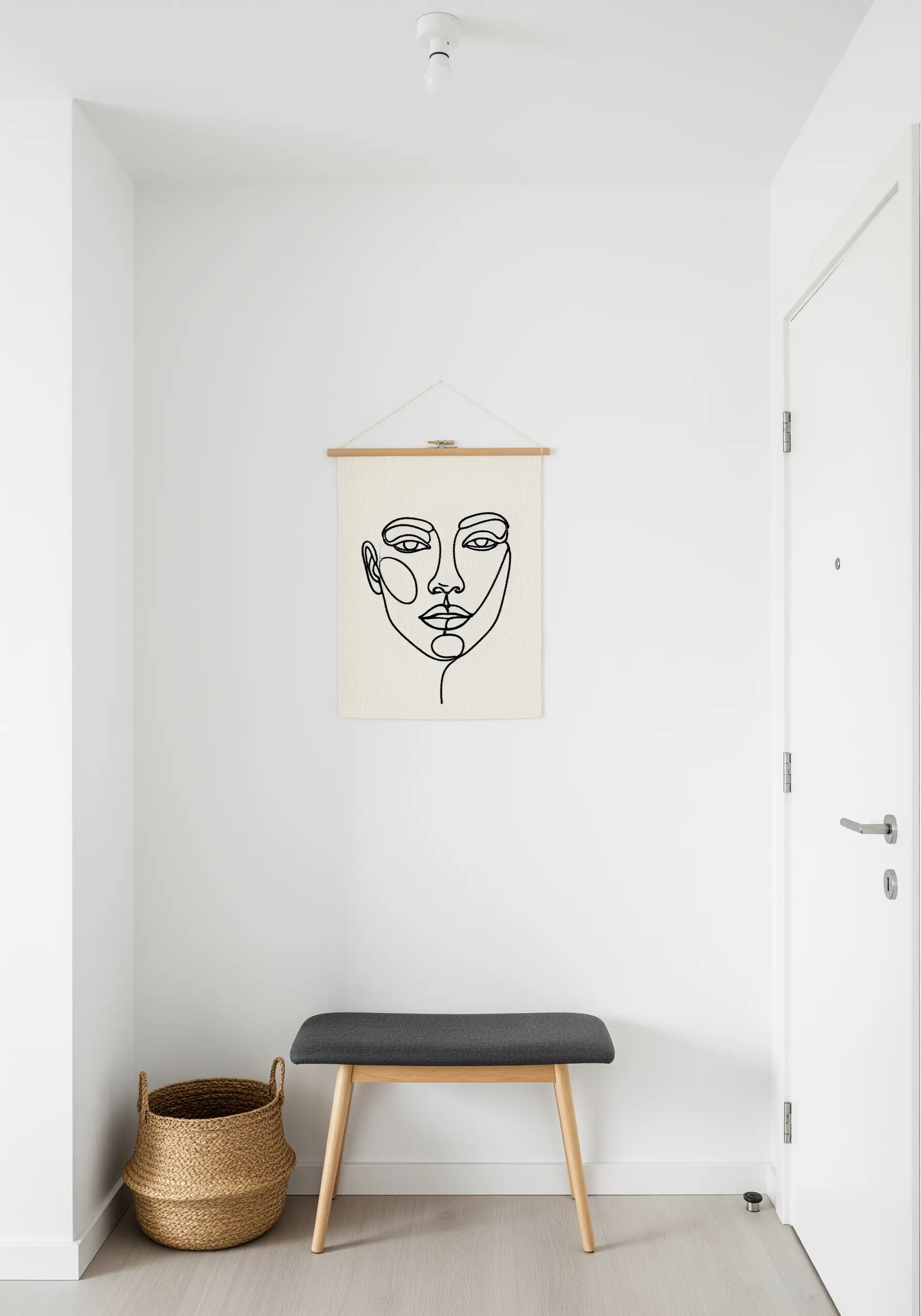 A small wall hanging with a minimalist one-line embroidered portrait of a face.