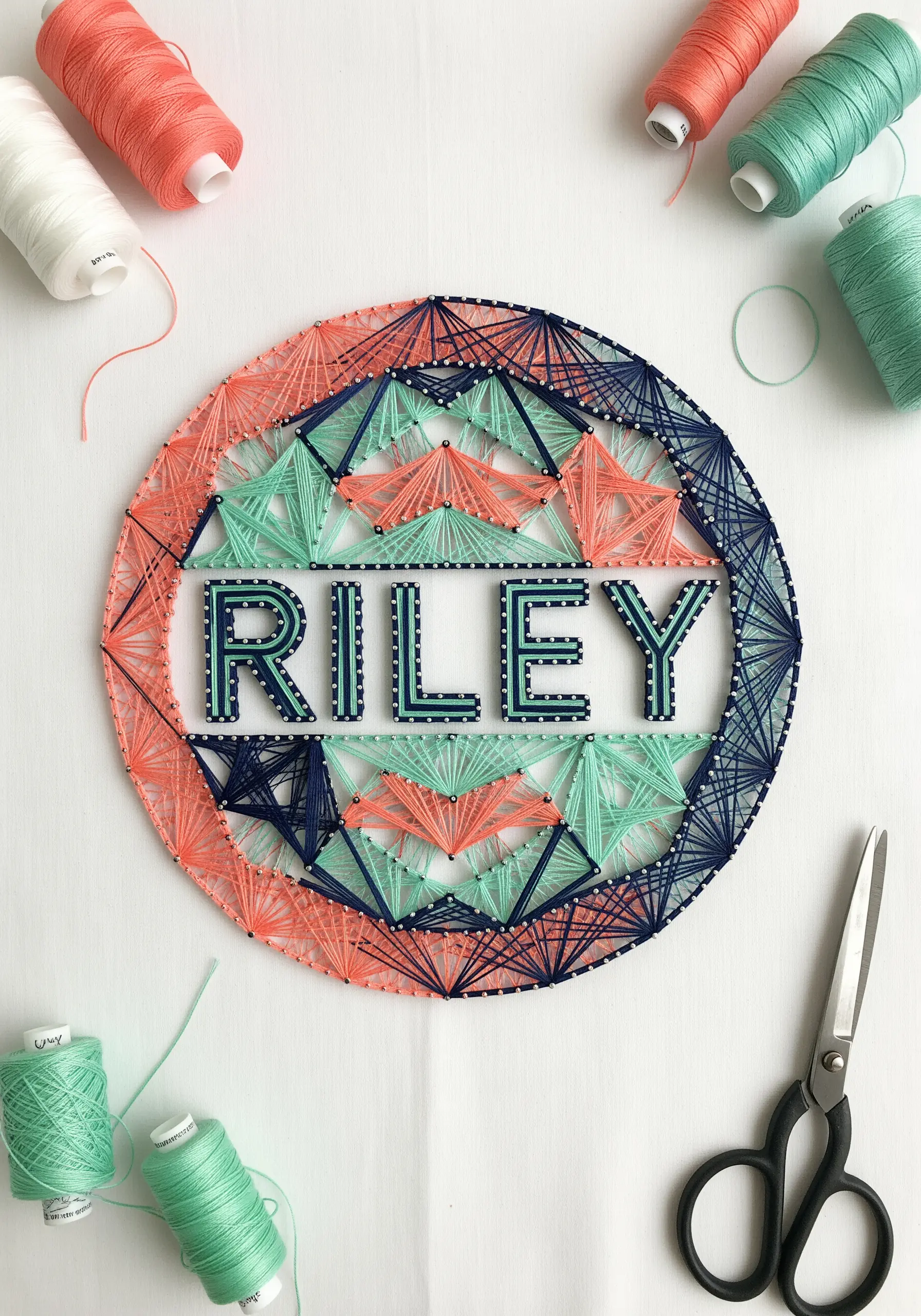 A name surrounded by a colorful, geometric mandala pattern stitched with straight lines.