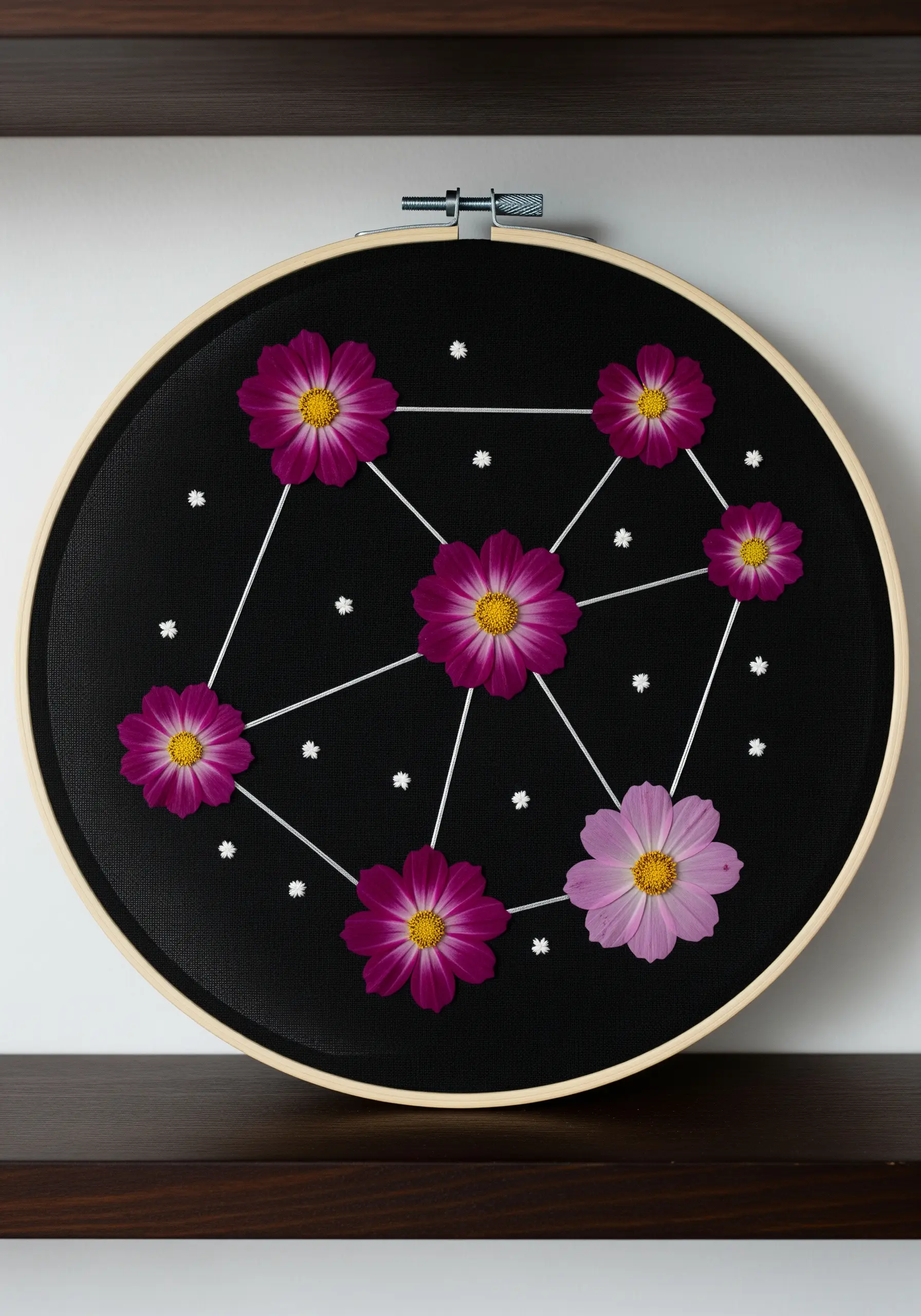Pressed cosmos flowers connected by stitched lines to form a constellation.