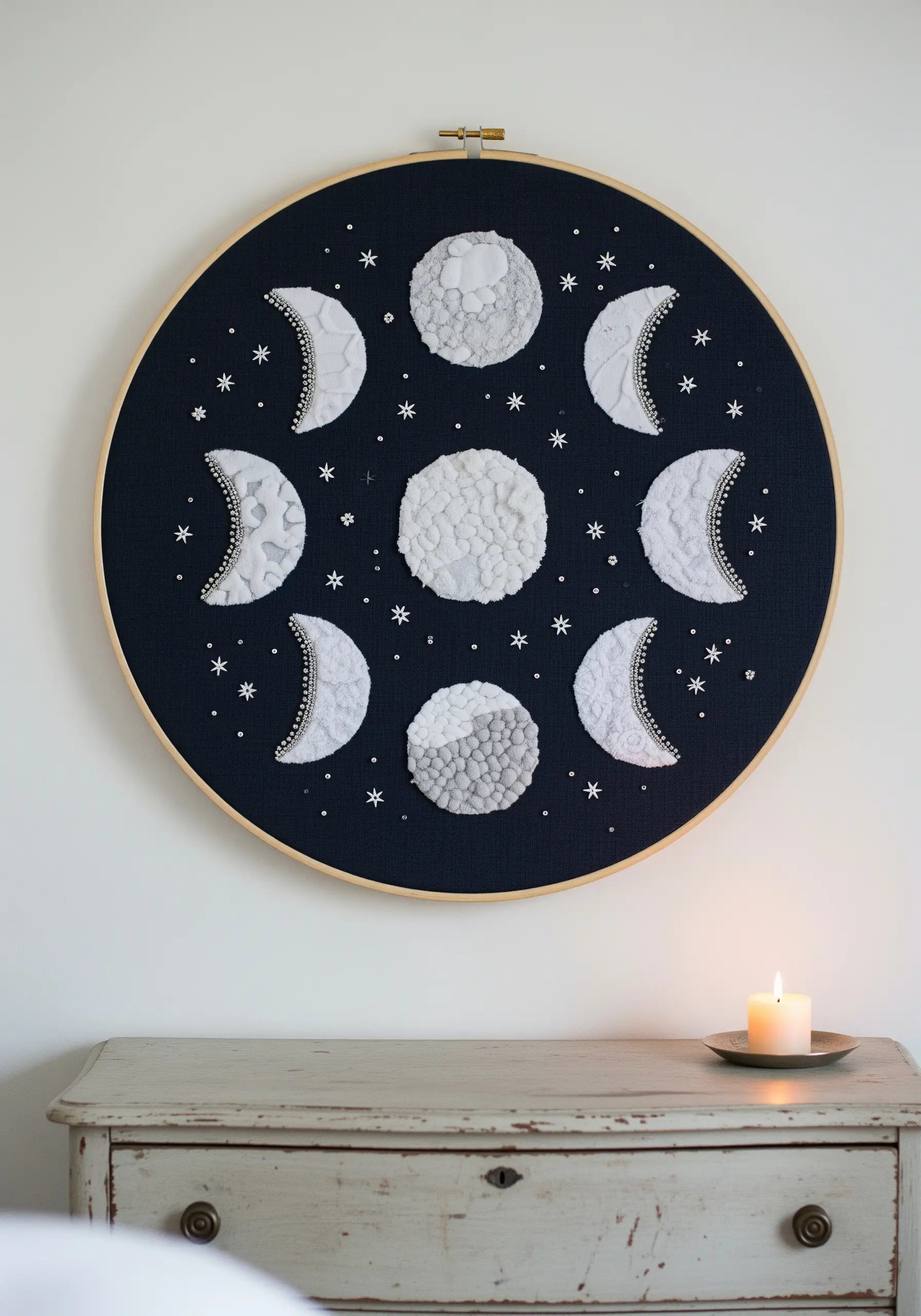 Embroidery of the moon phases with highly textured, white-on-black stitching.